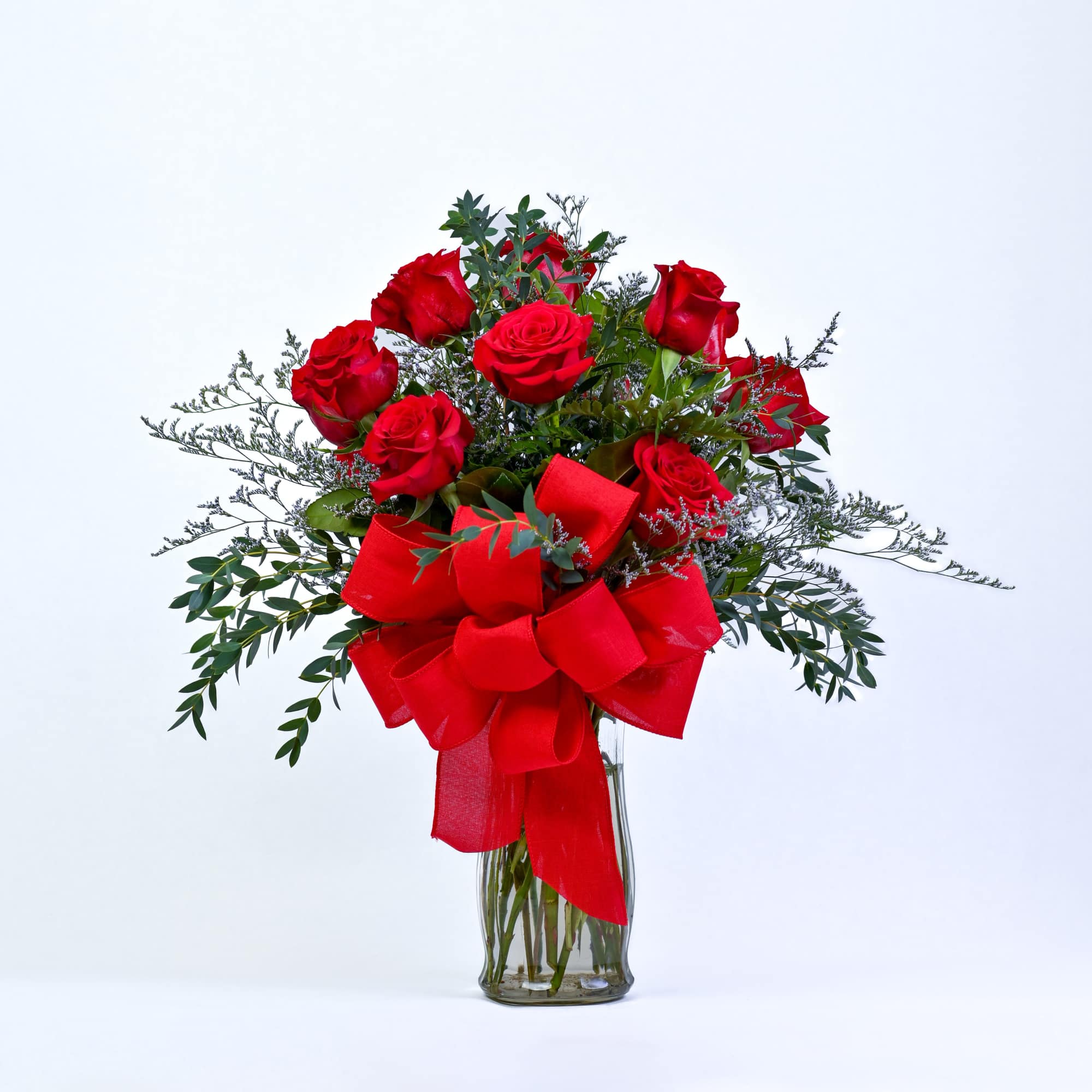 Red roses in a clear glass vase with a large red bow