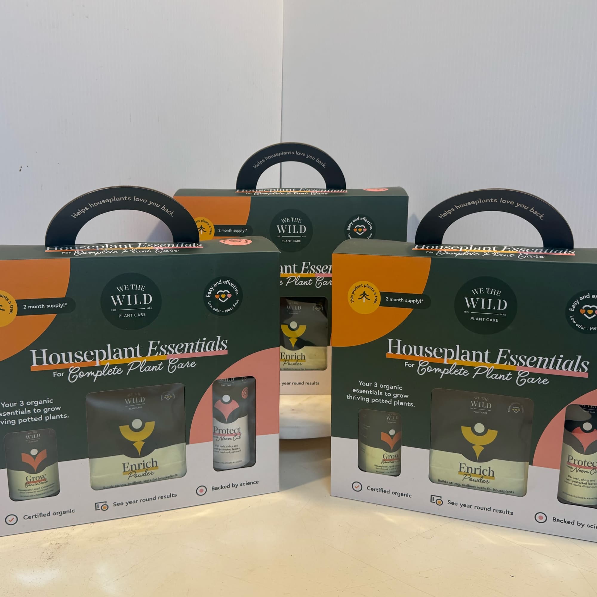Three houseplant care kits in dark green and orange boxes.