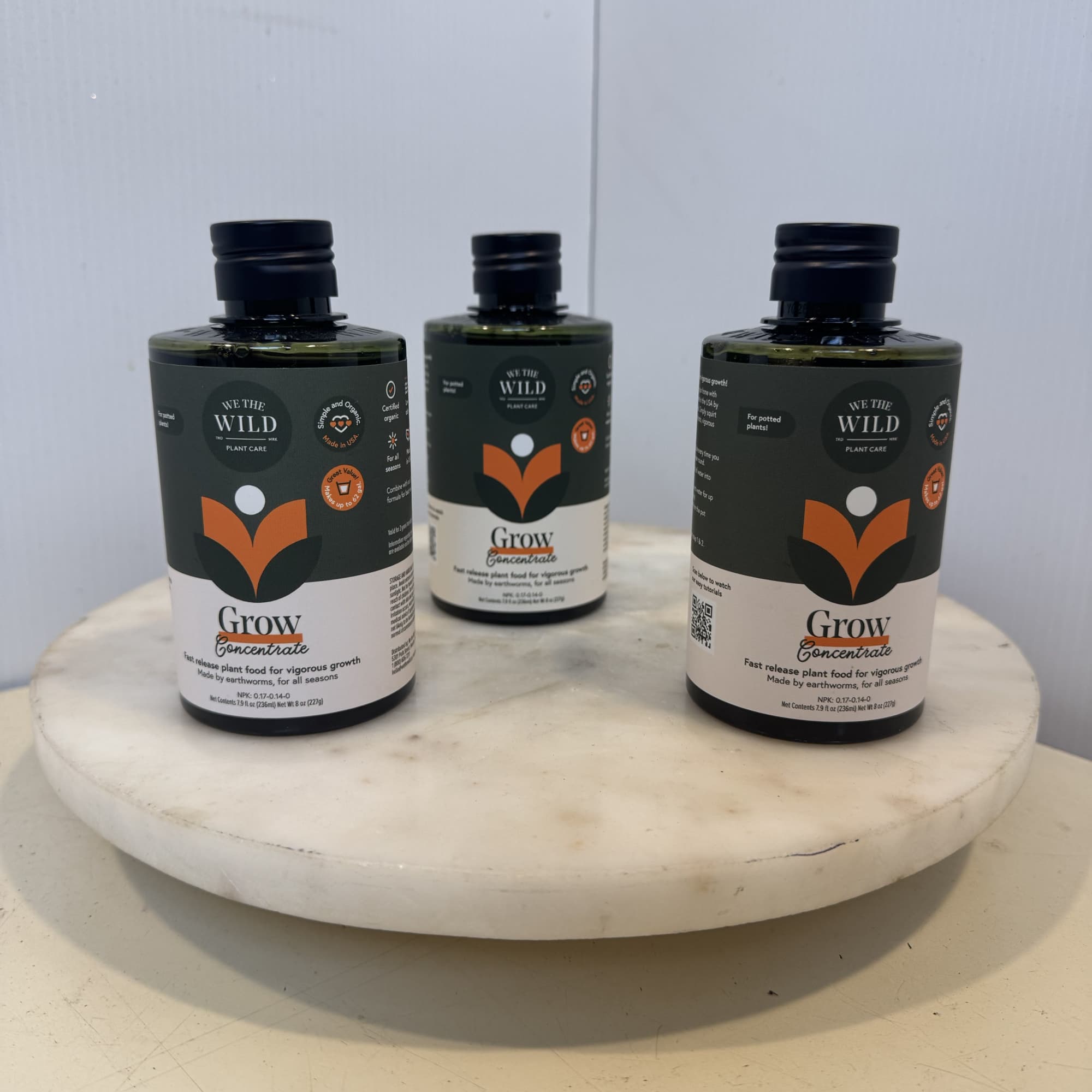 Three plant care bottles on a round white pedestal