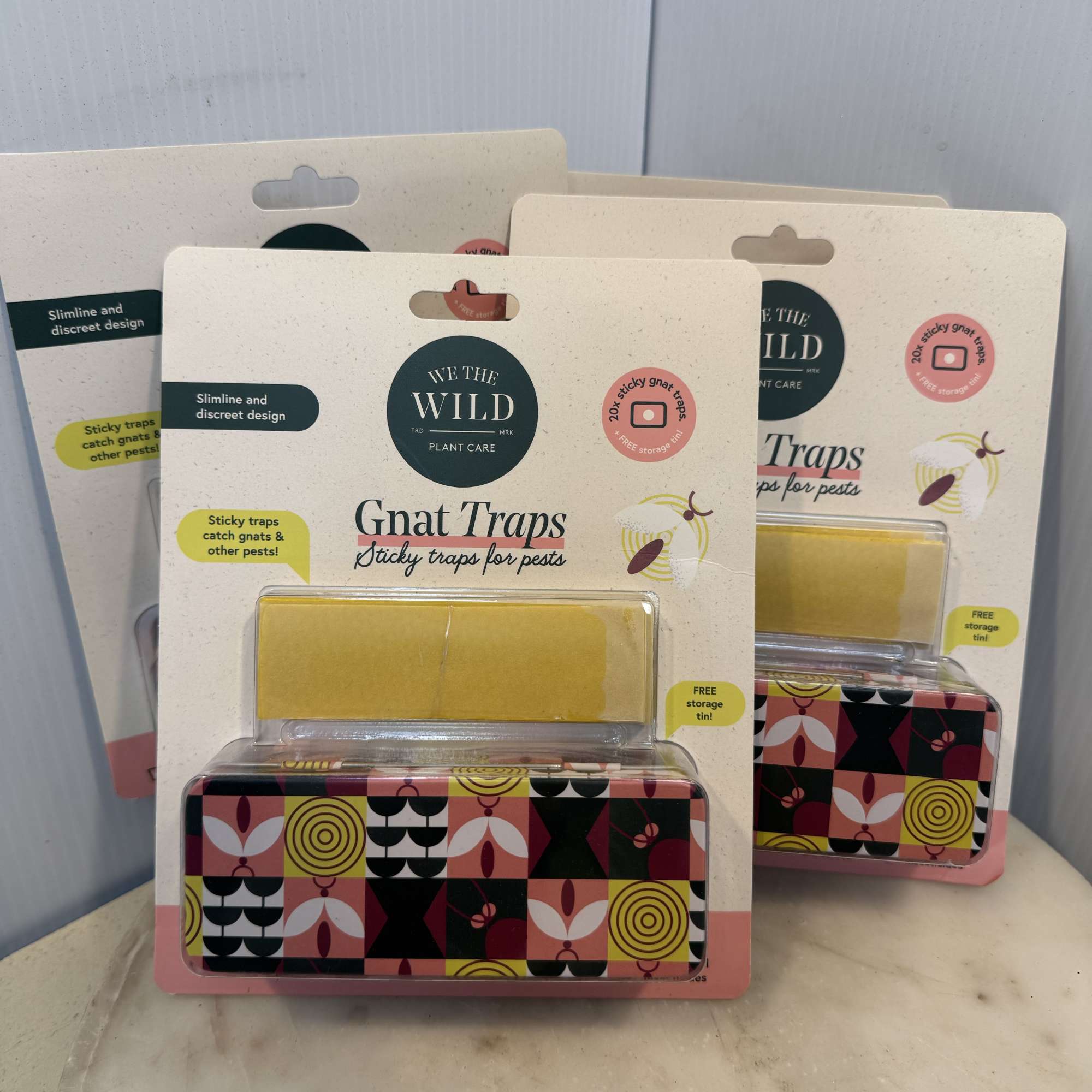 Three packaged gnat traps with patterned tins on a tabletop