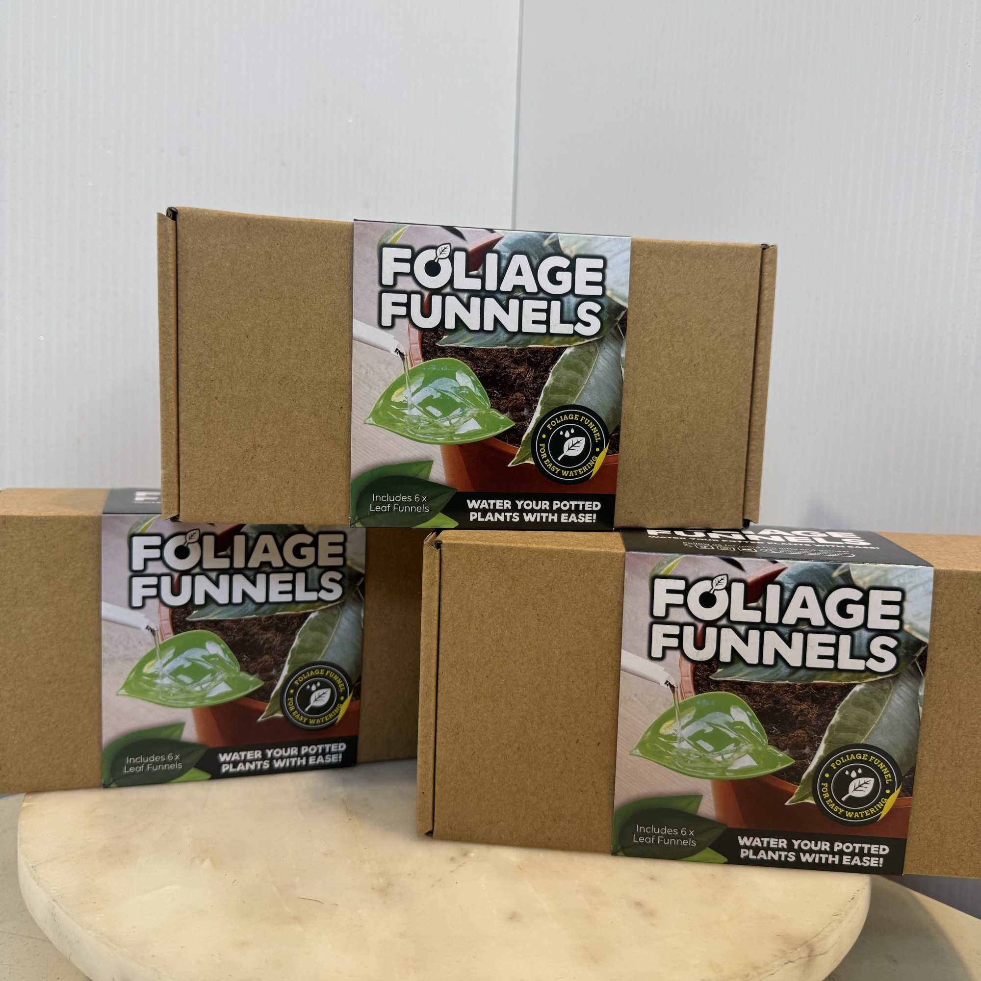 Three cardboard boxes of foliage funnels stacked on a round pedestal.