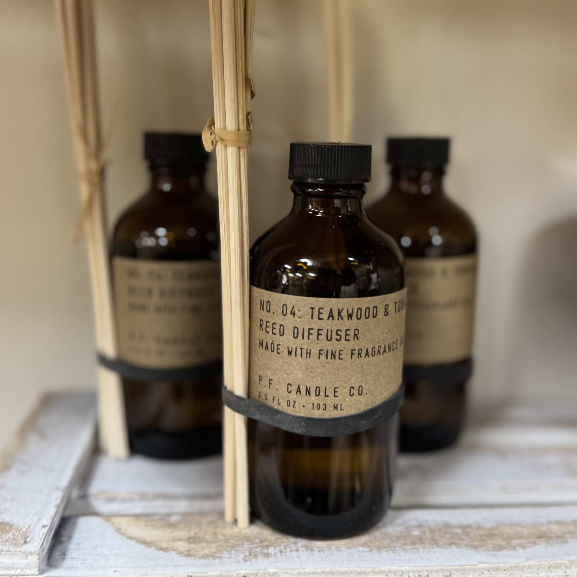 Amber reed diffuser bottles with wooden sticks on a shelf
