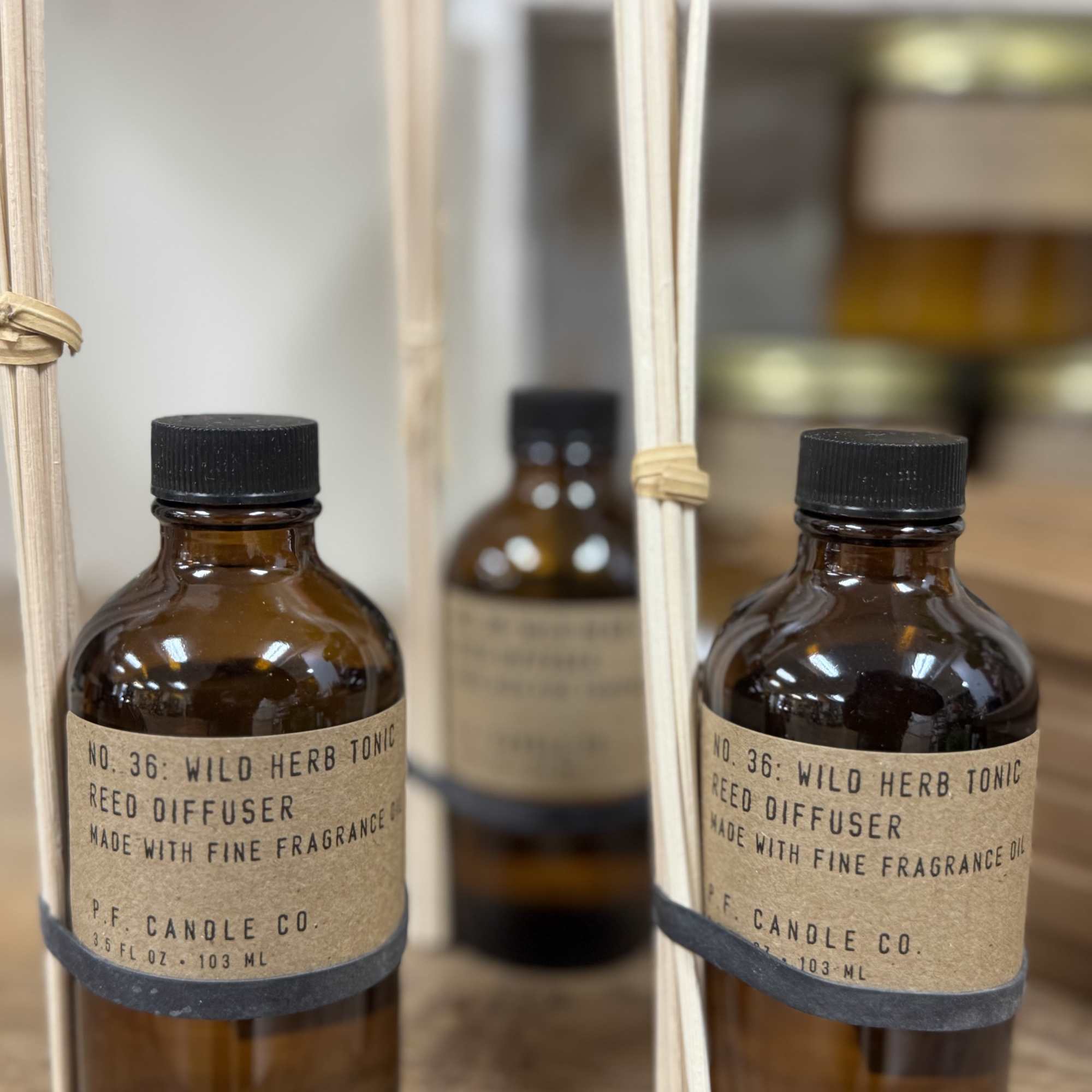 Two amber reed diffuser bottles with black caps and reeds