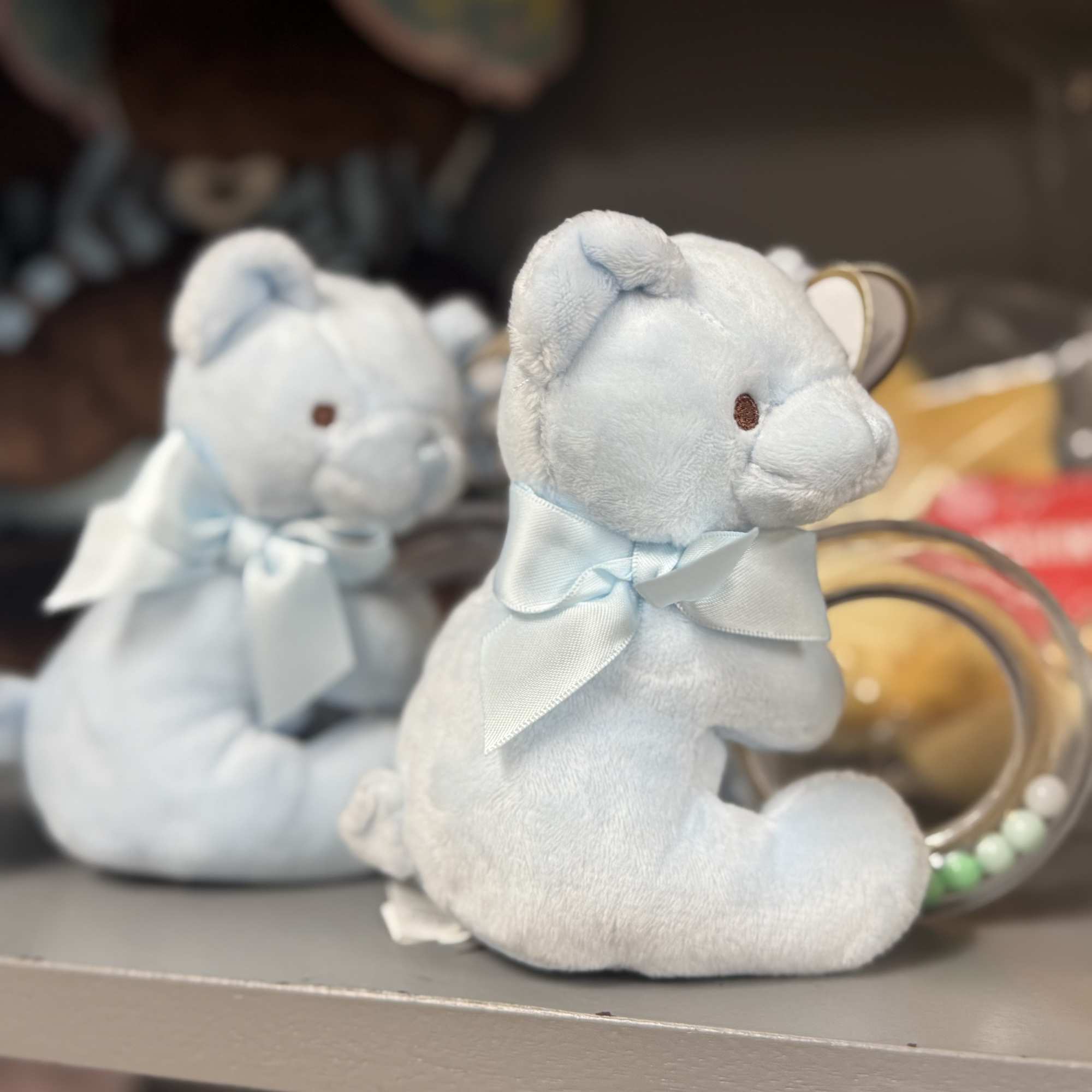 Two light blue teddy bears with ribbons on a shelf