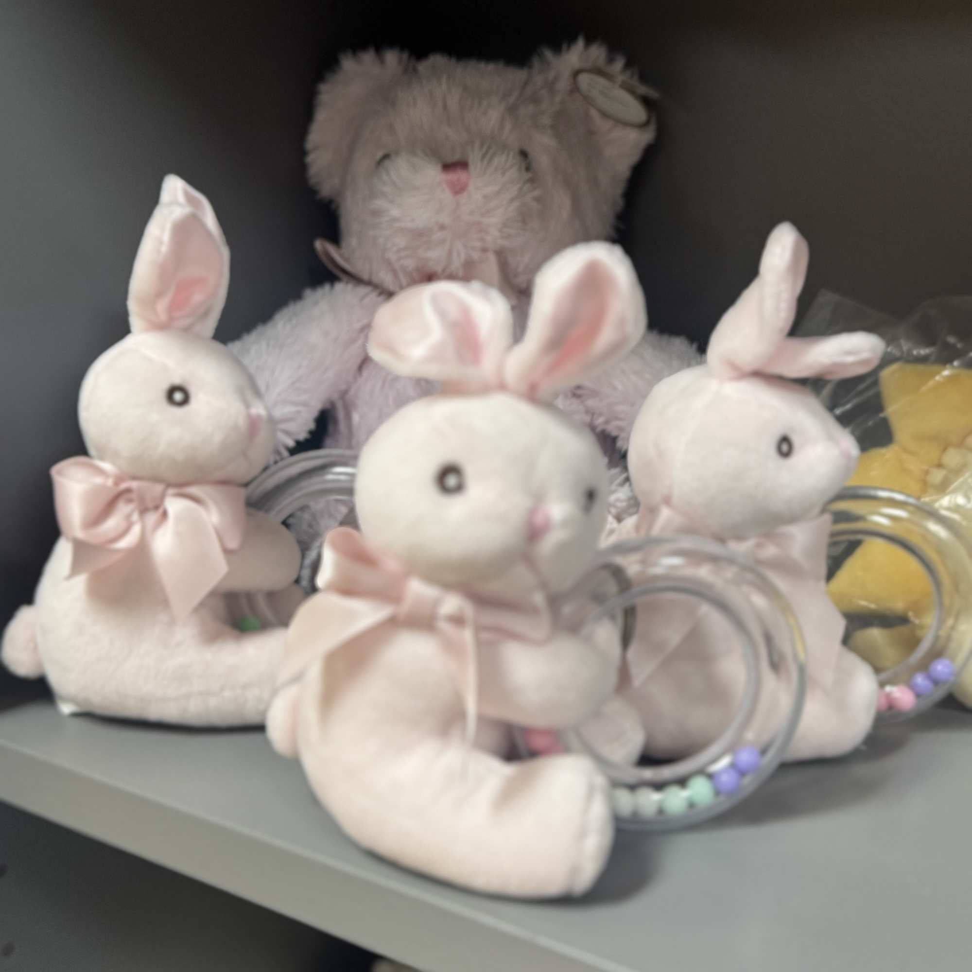 Plush bunny figurines with pink bows on a shelf