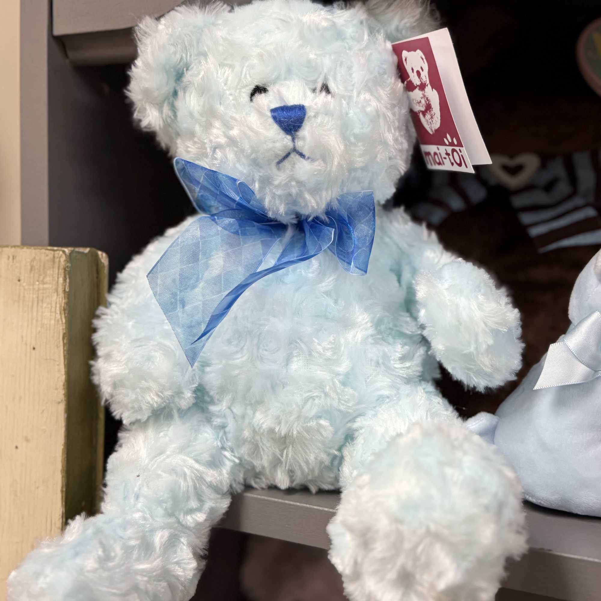 Light blue plush teddy bear with a blue ribbon