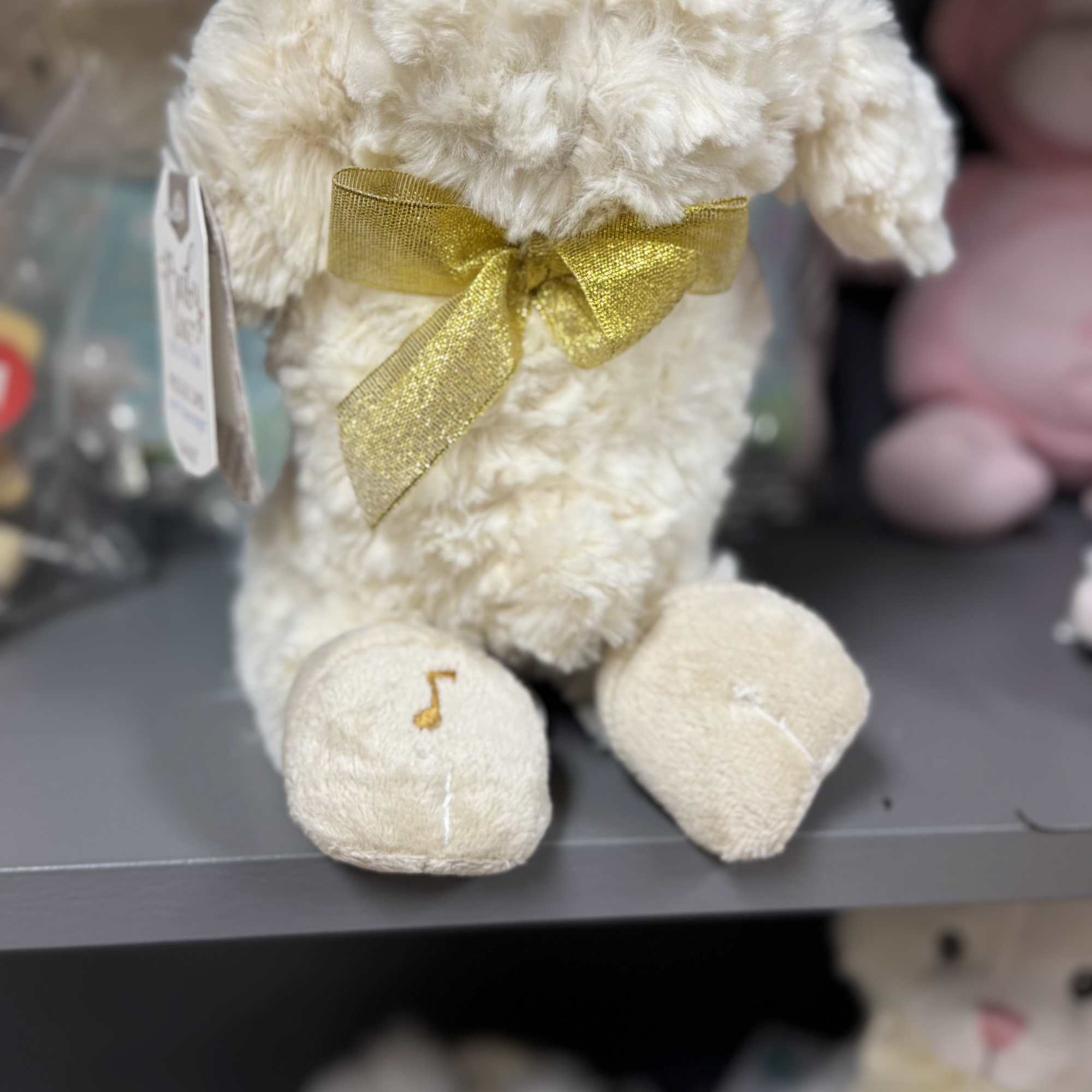 Cream plush teddy bear with a gold ribbon bow
