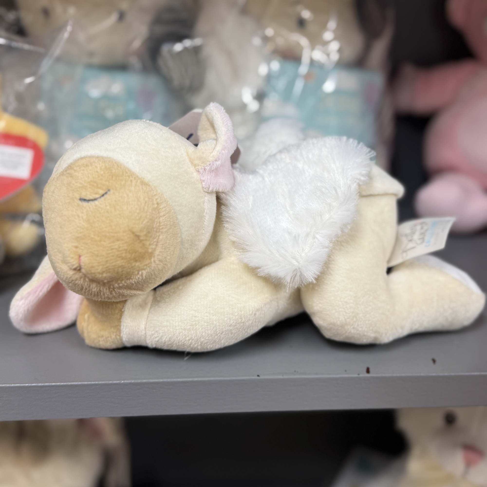 Plush lamb toy lying on a shelf