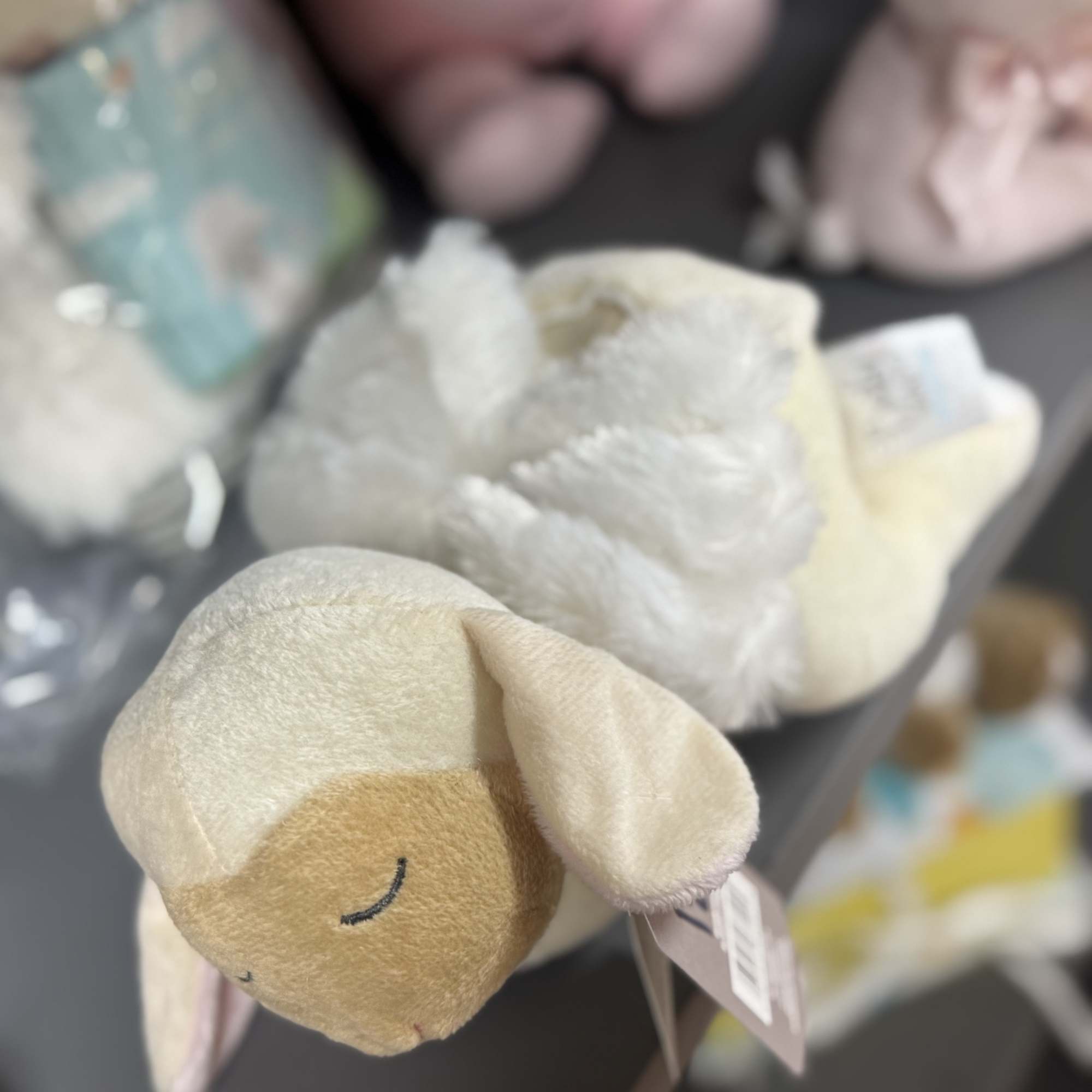 Plush sheep toys in soft pastel colors on a shelf