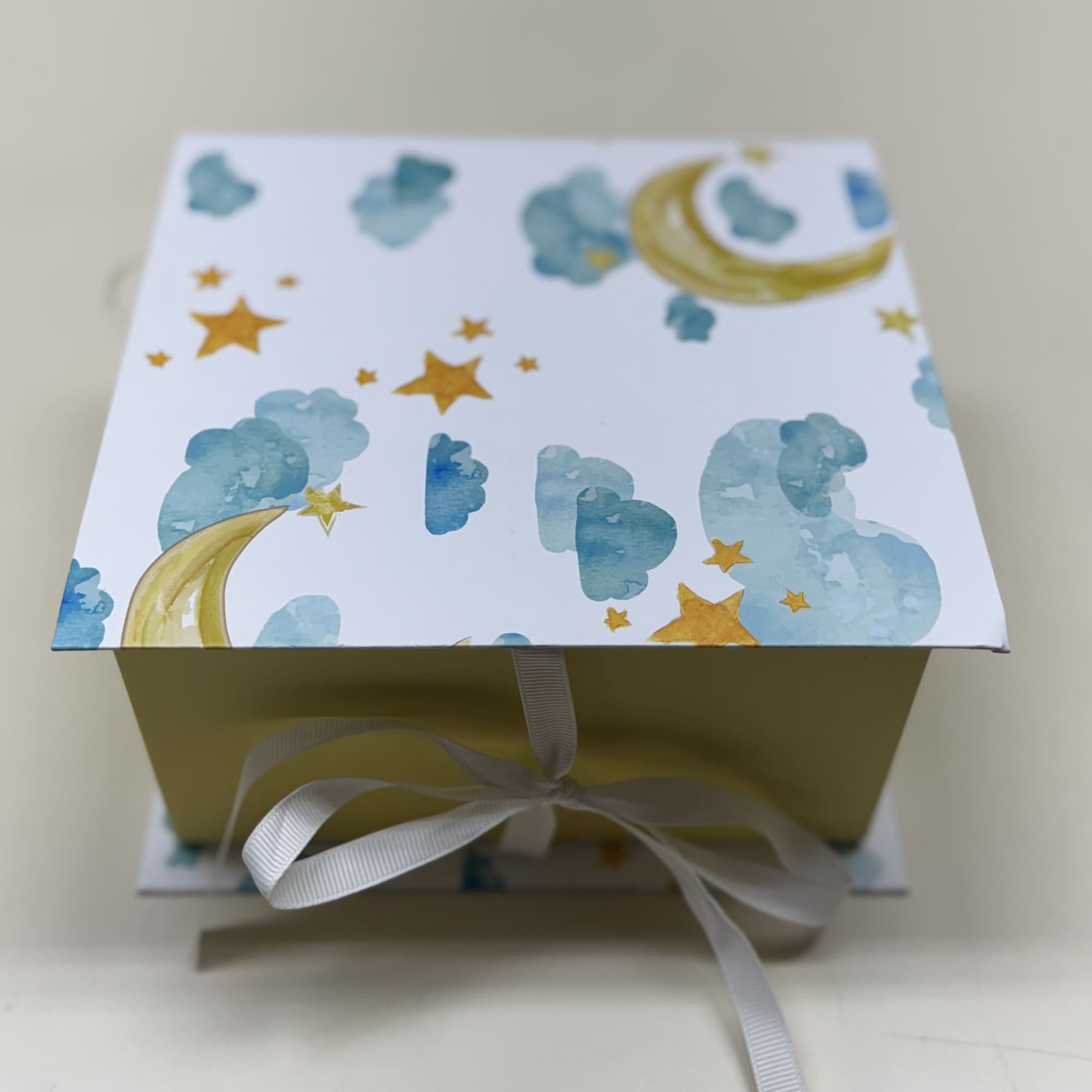Decorative gift box with moon and stars pattern and a white ribbon