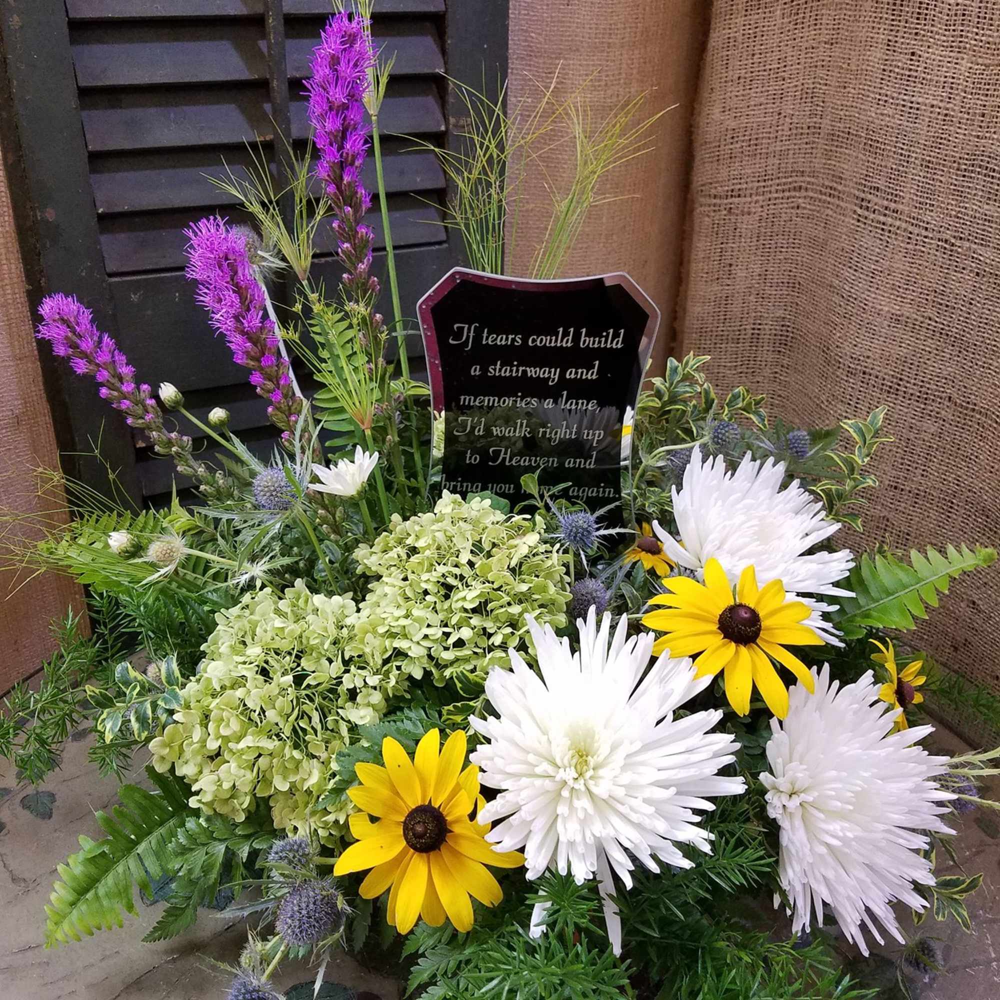 Sympathy floral arrangement with white and yellow daisies and purple accents