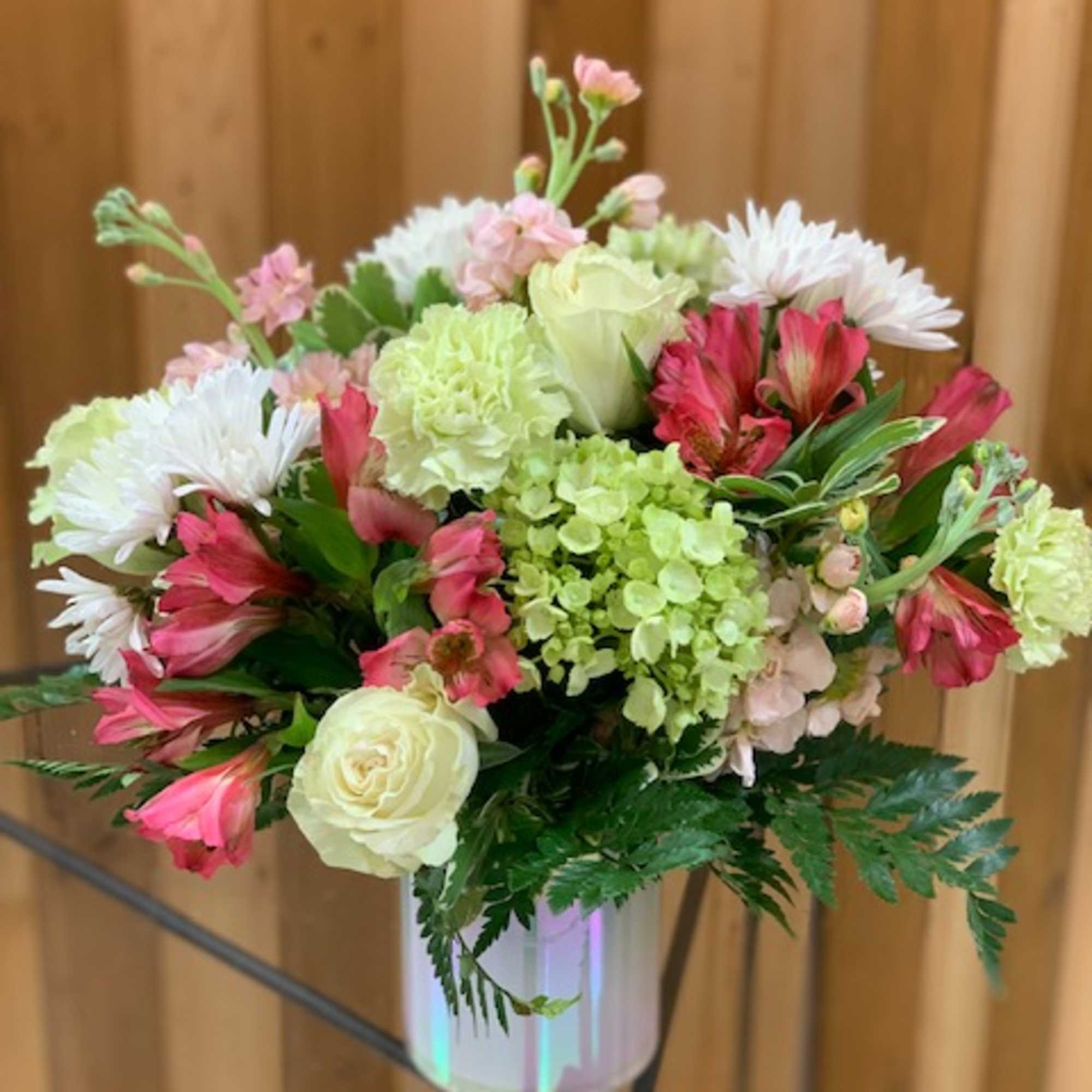 Mixed pink, white, and green flowers in a white vase