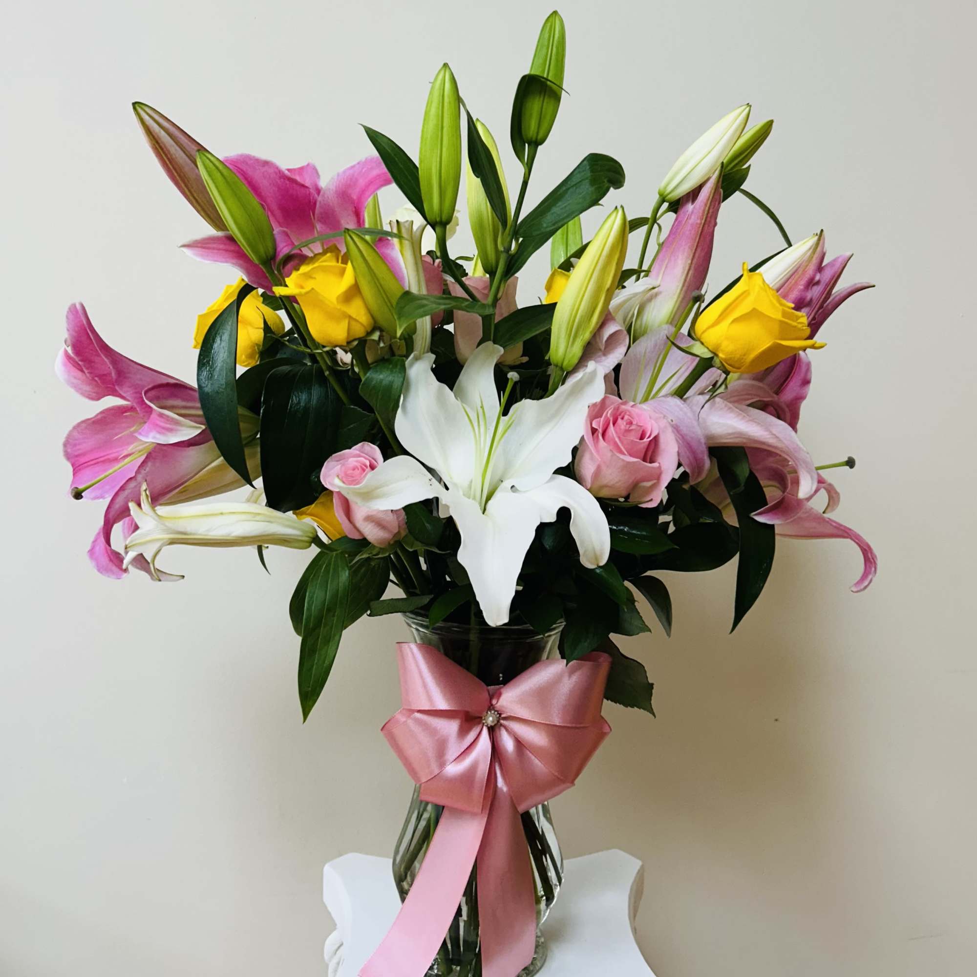 Bouquet of pink and white lilies with yellow roses in a glass vase