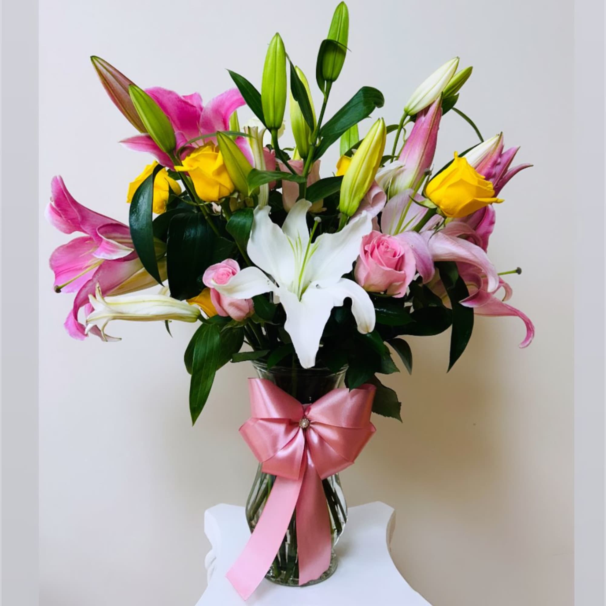 Bouquet of pink and white lilies with yellow roses in a glass vase