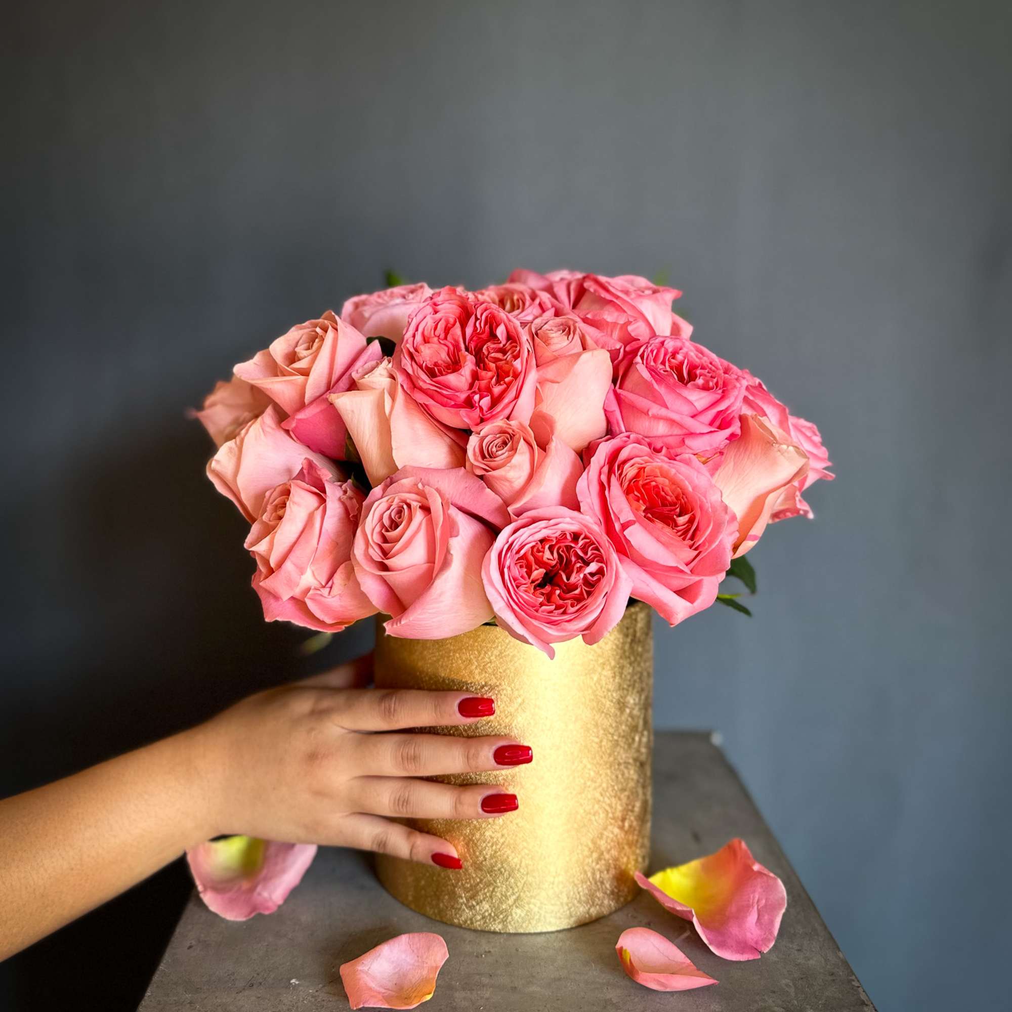 Pink roses arranged in a gold cylindrical vase