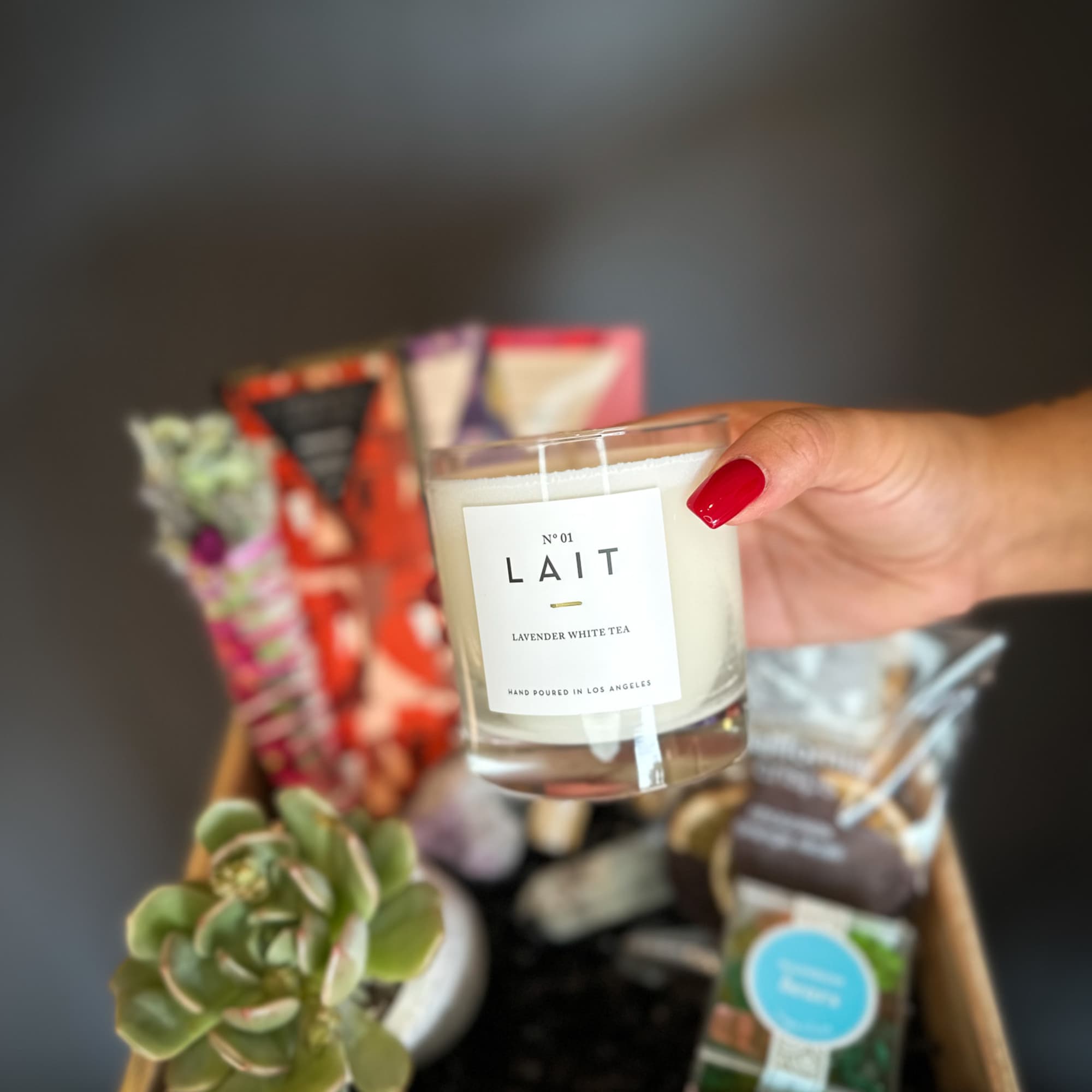 Gift basket with a candle, succulent, and assorted packaged treats