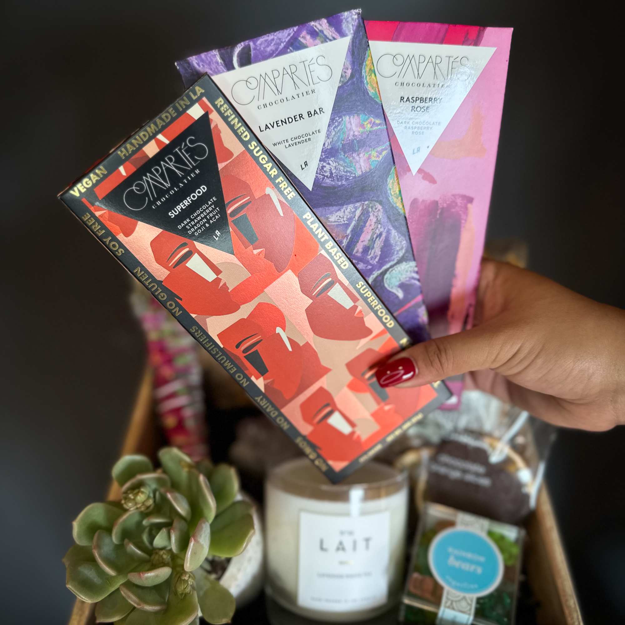 Gift basket with chocolate bars, a candle, and a small succulent