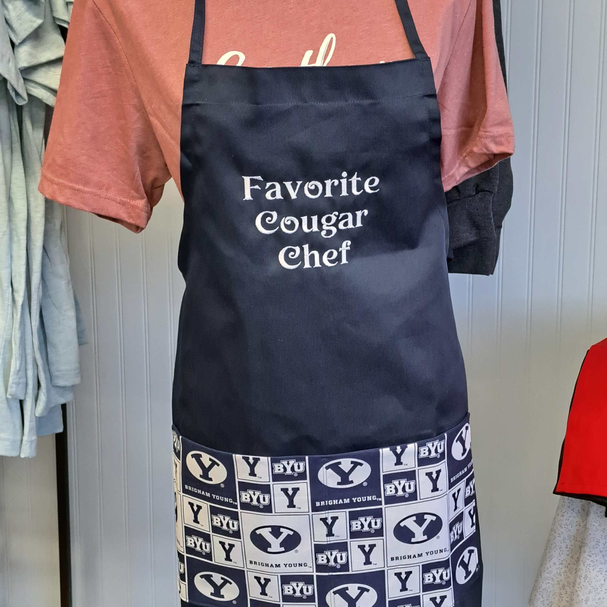 Navy apron over a pink T-shirt with BYU logos and text