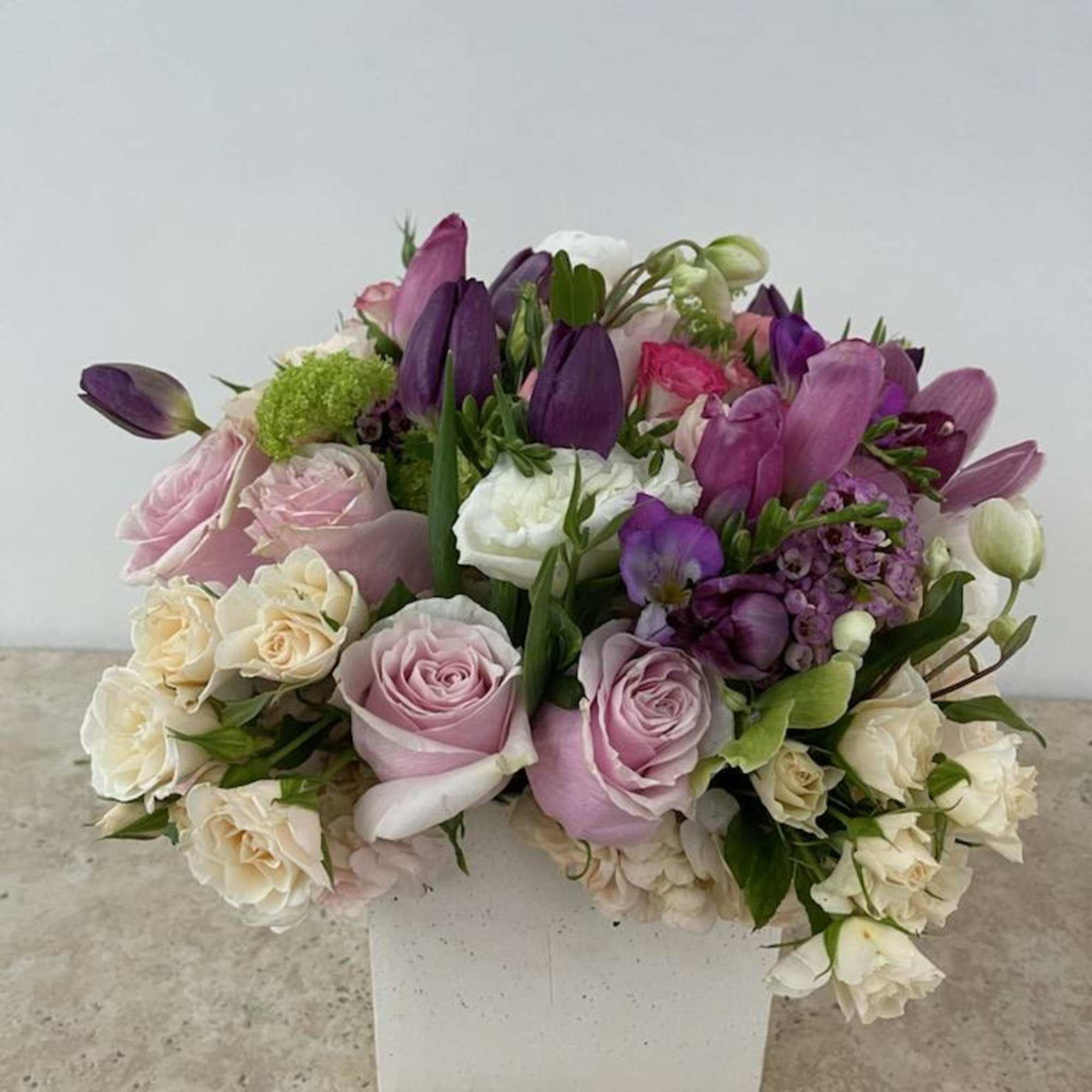 Bouquet of pink, white, and purple flowers in a white box