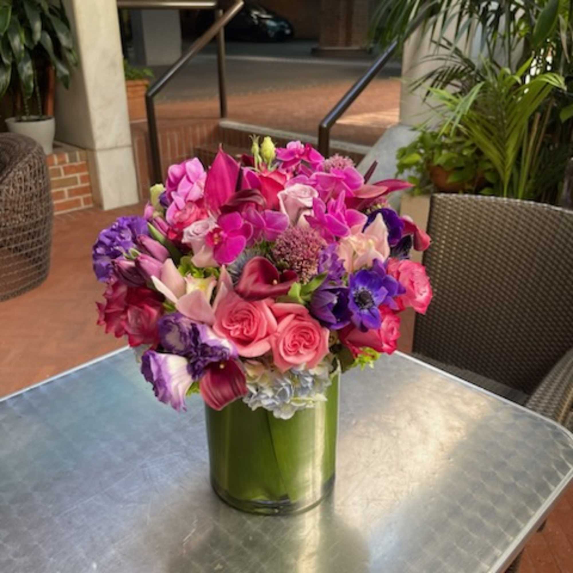 Pink and purple mixed bouquet in a green glass vase