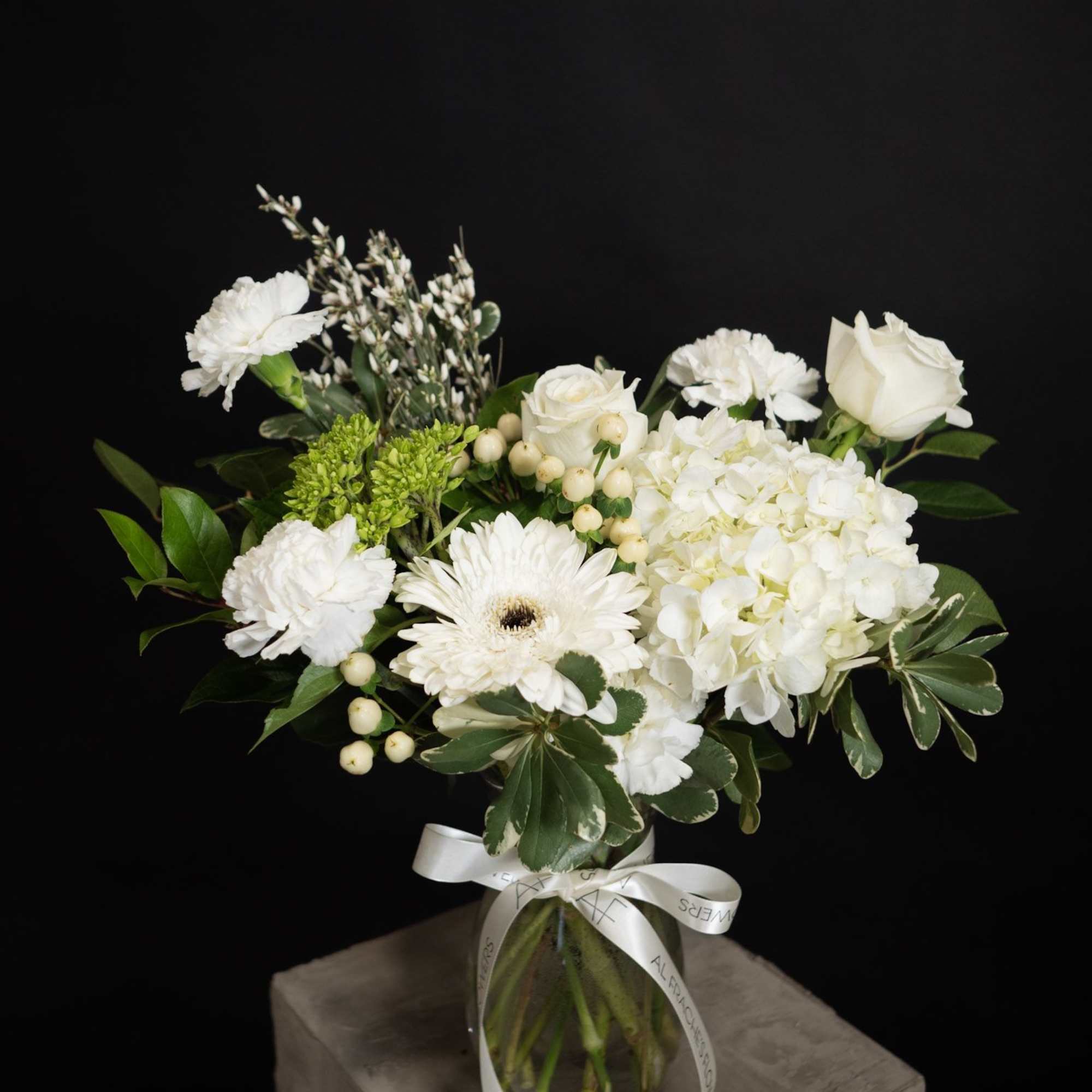 White floral bouquet in a glass vase with a ribbon bow