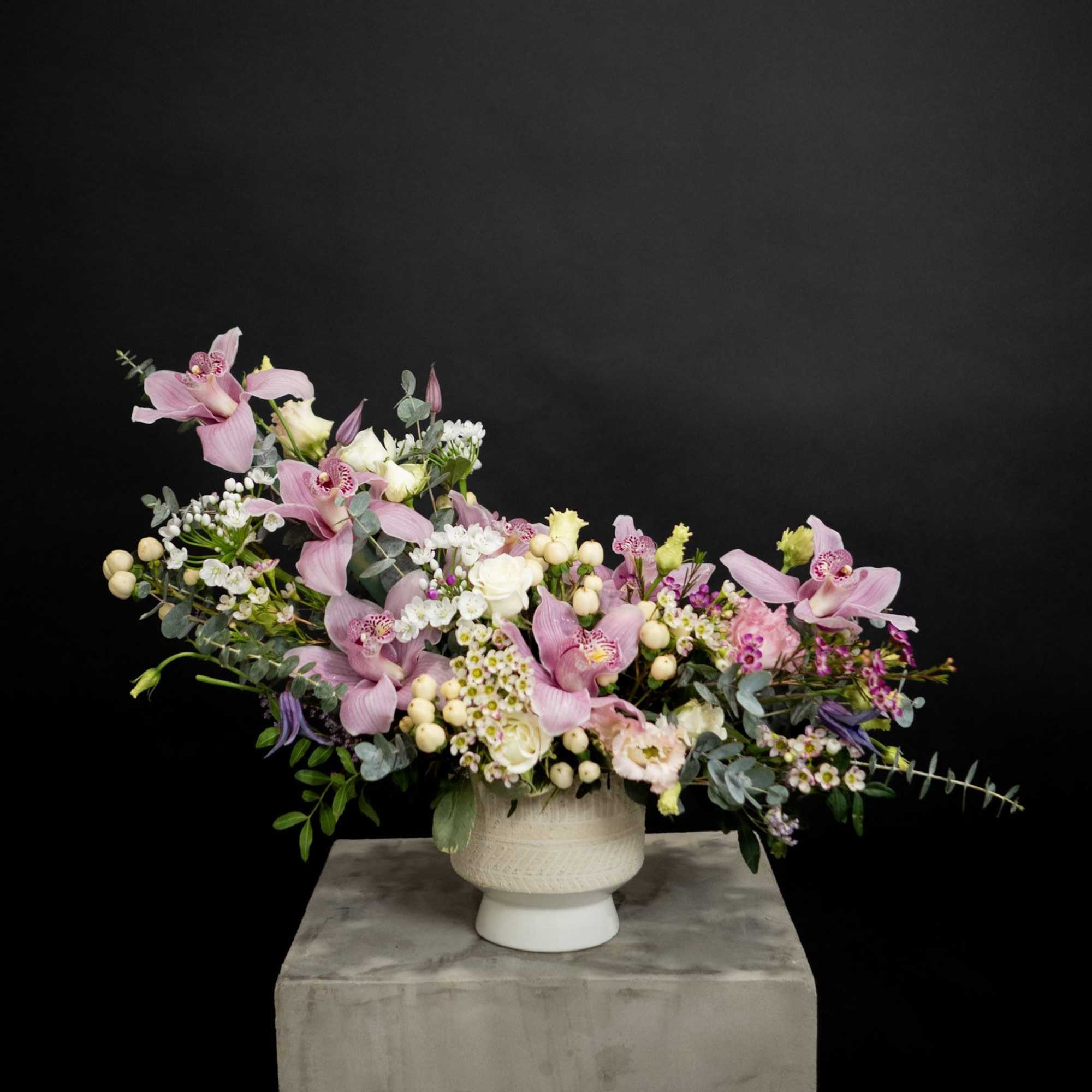Pink orchid and mixed flower arrangement in a white vase