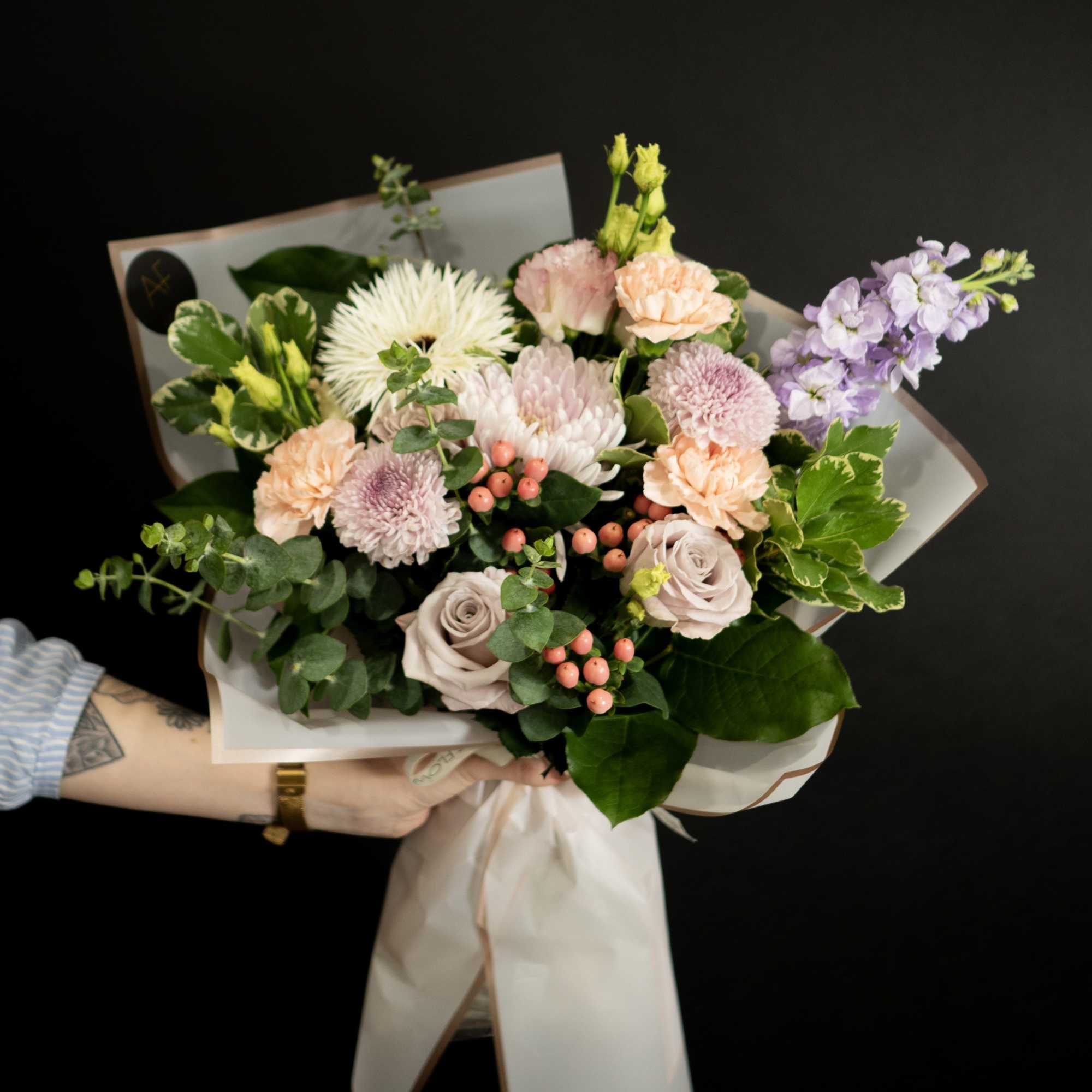Hand-tied bouquet of pastel flowers with a white wrap