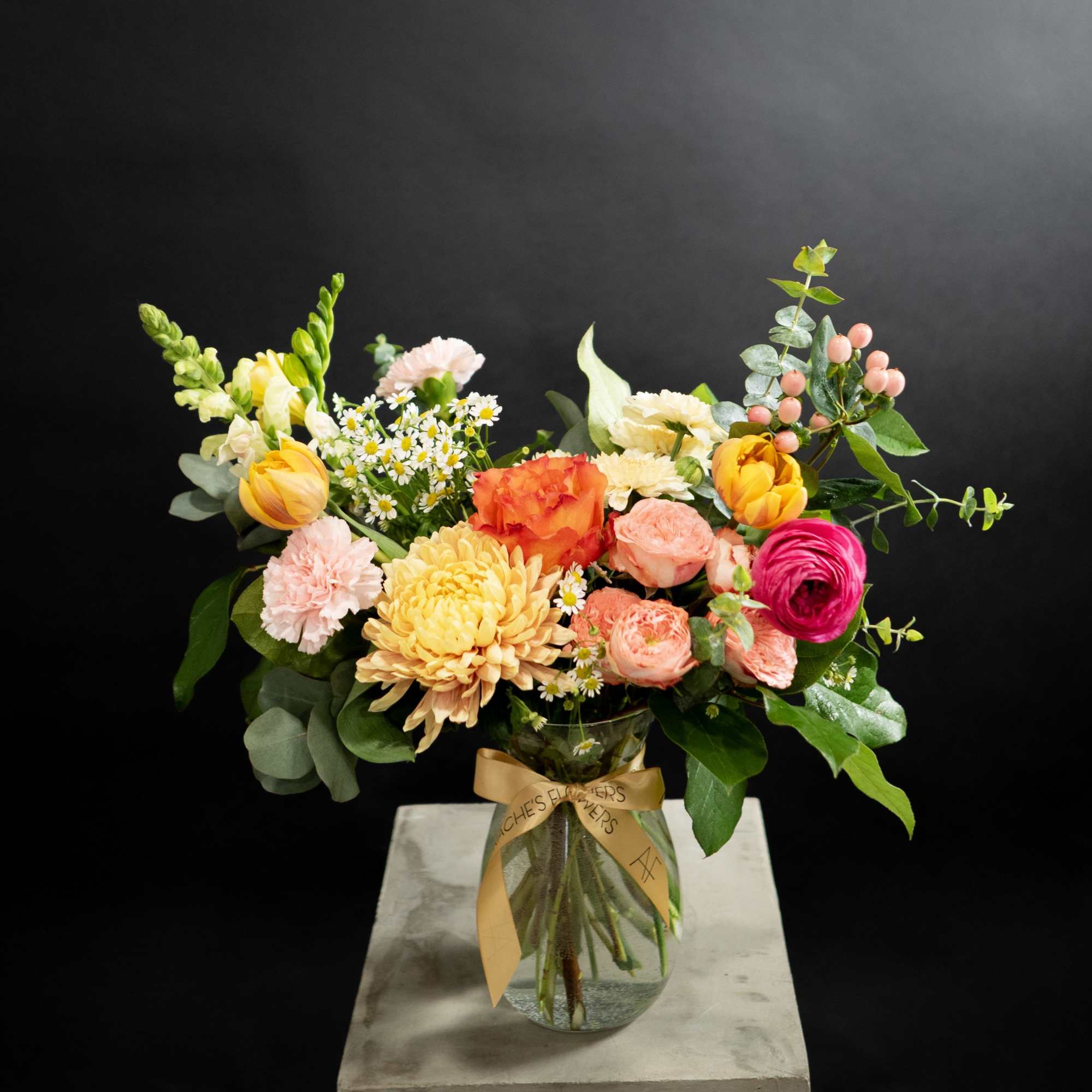 Mixed bouquet in a glass vase with pink, yellow, orange, and white flowers