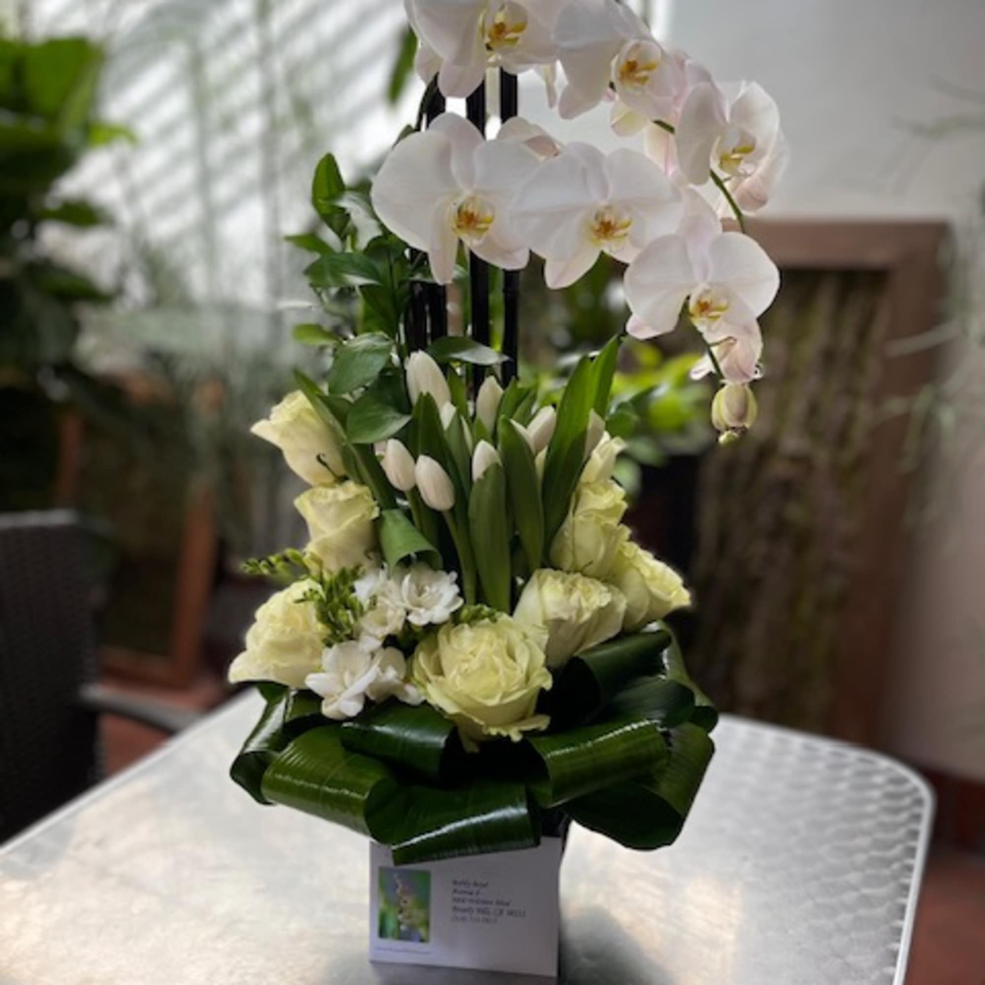 White orchids and pale roses in a tall arrangement
