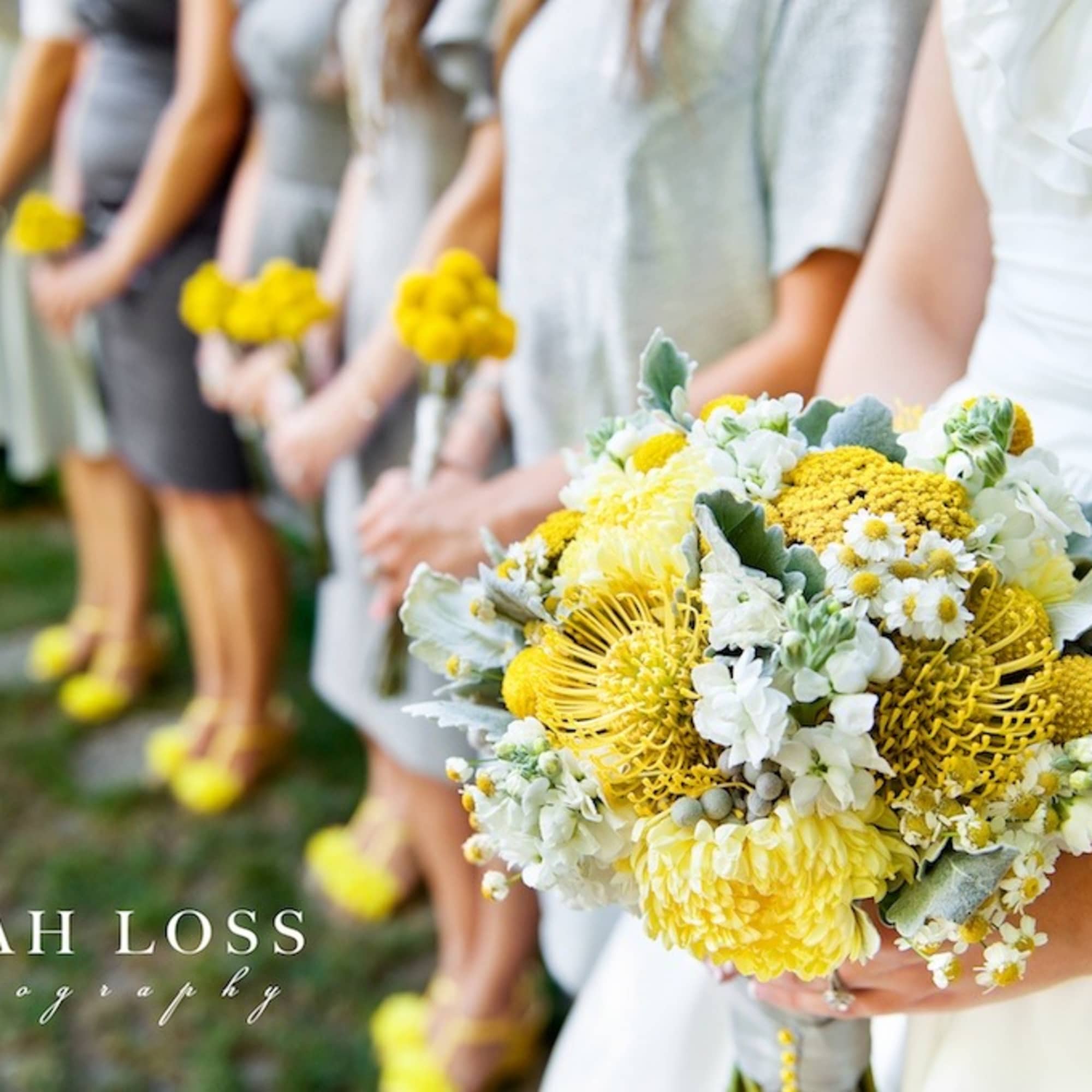Bride holding a yellow and white bouquet with bridesmaids in the background