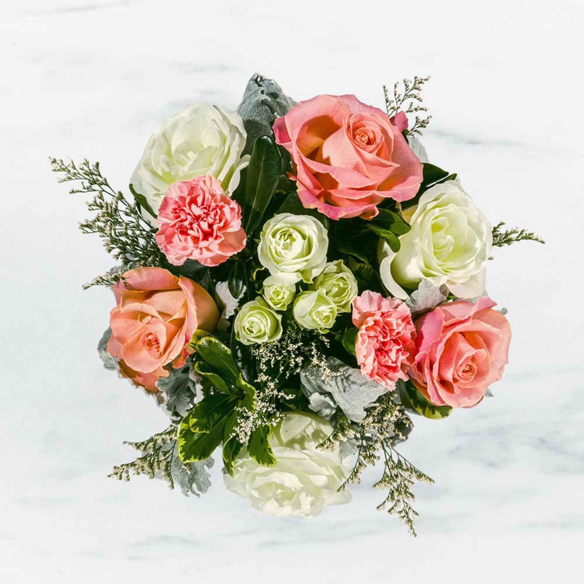 This arrangement includes pink roses, white roses, white spray roses, pink carnations
