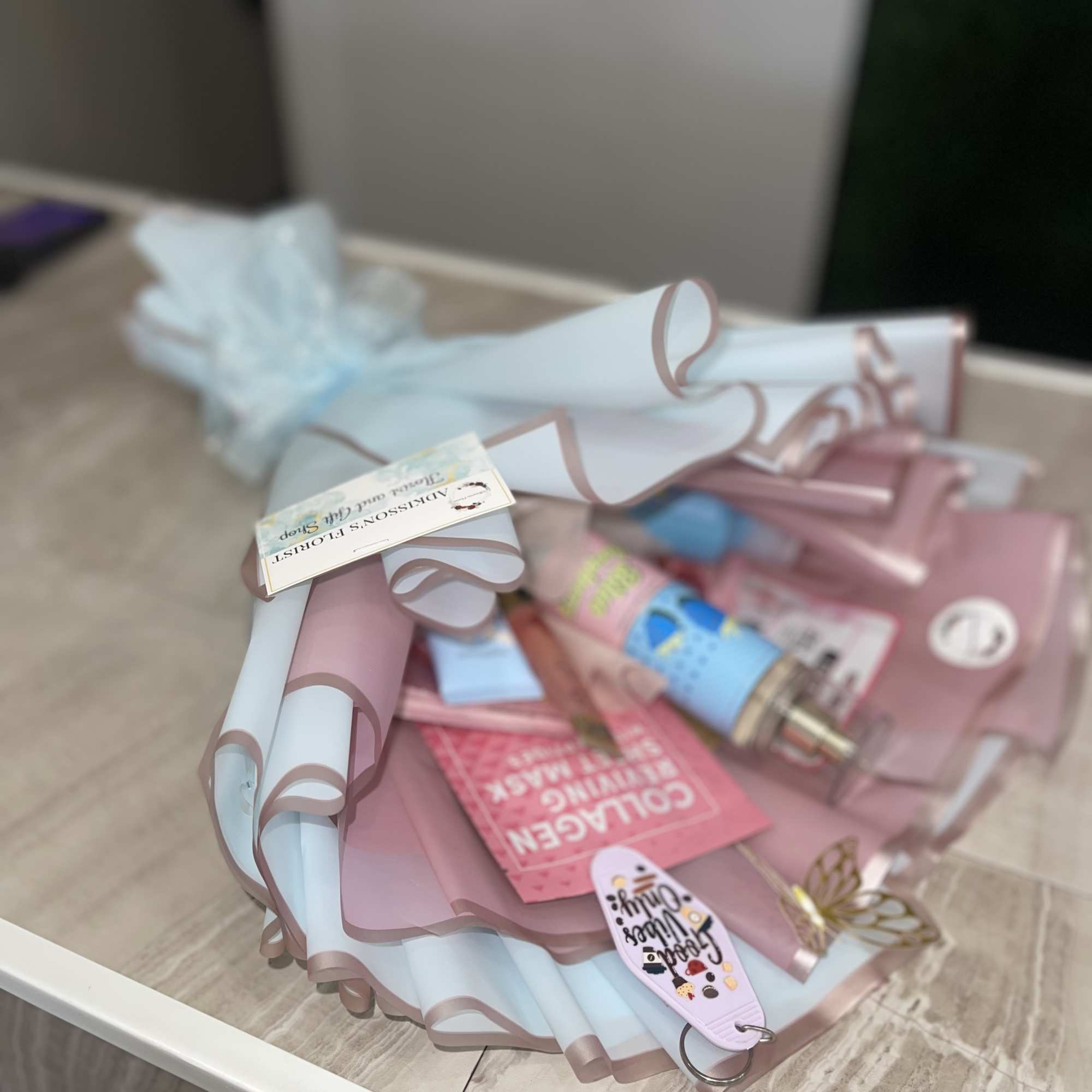 Pastel gift bundle with rolled wrapping paper, ribbons, and small beauty items