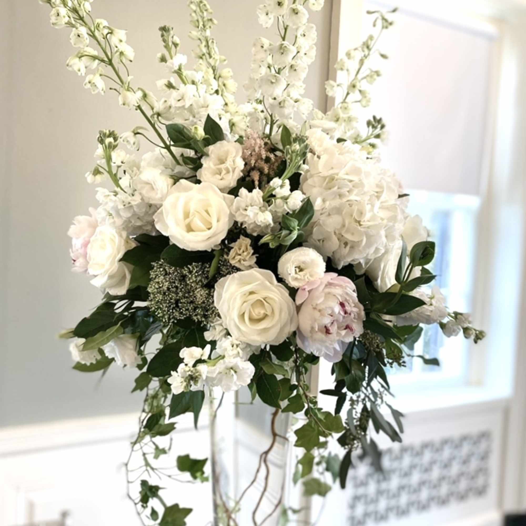 Tall white floral arrangement in a clear glass vase