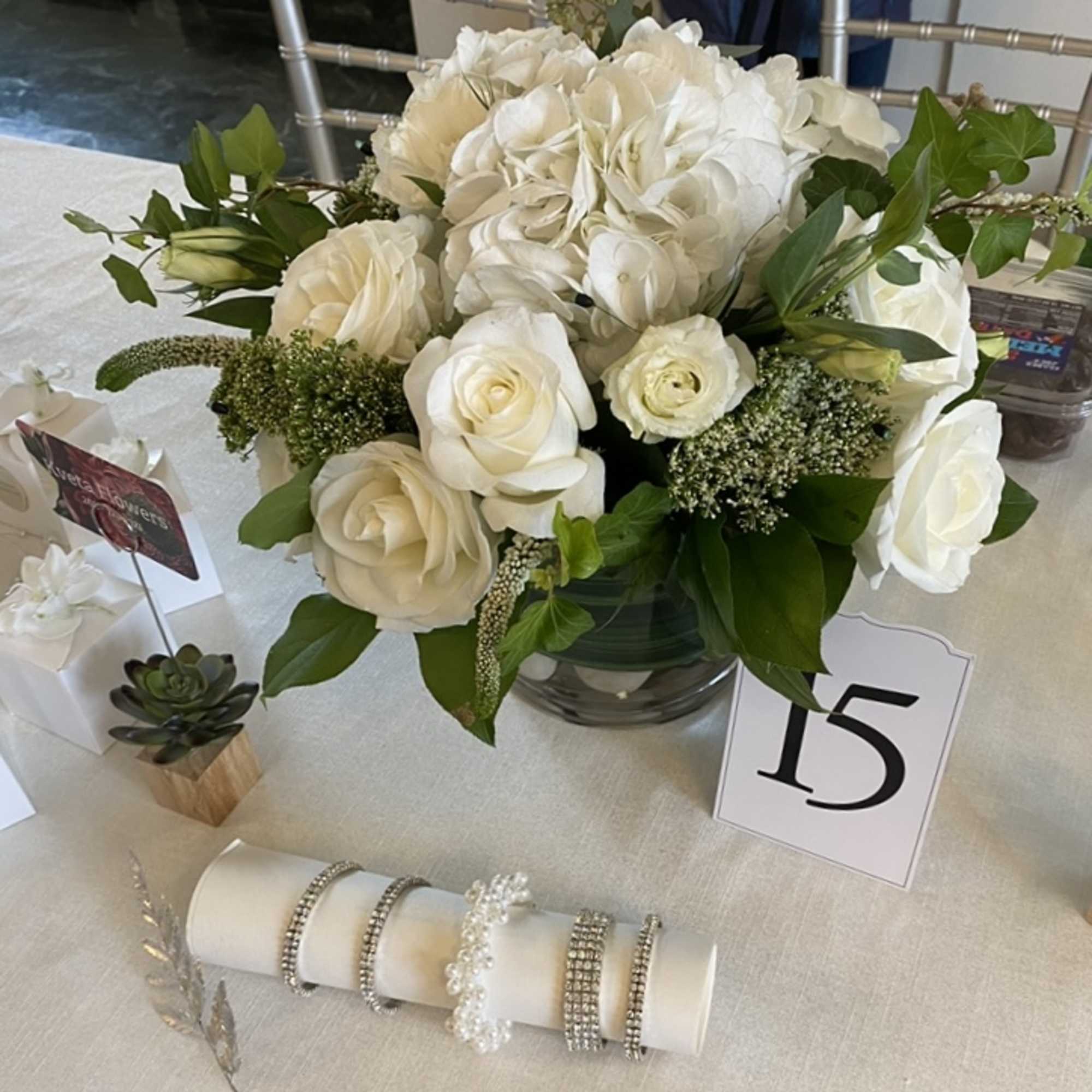 White rose and hydrangea centerpiece in a glass vase on a table