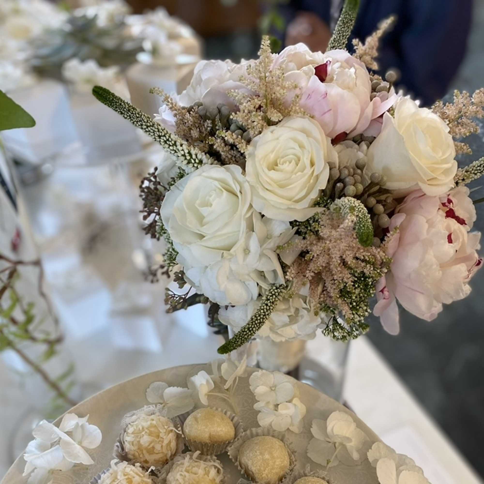 White and blush bouquet with roses and peonies, plus a tray of white sweets