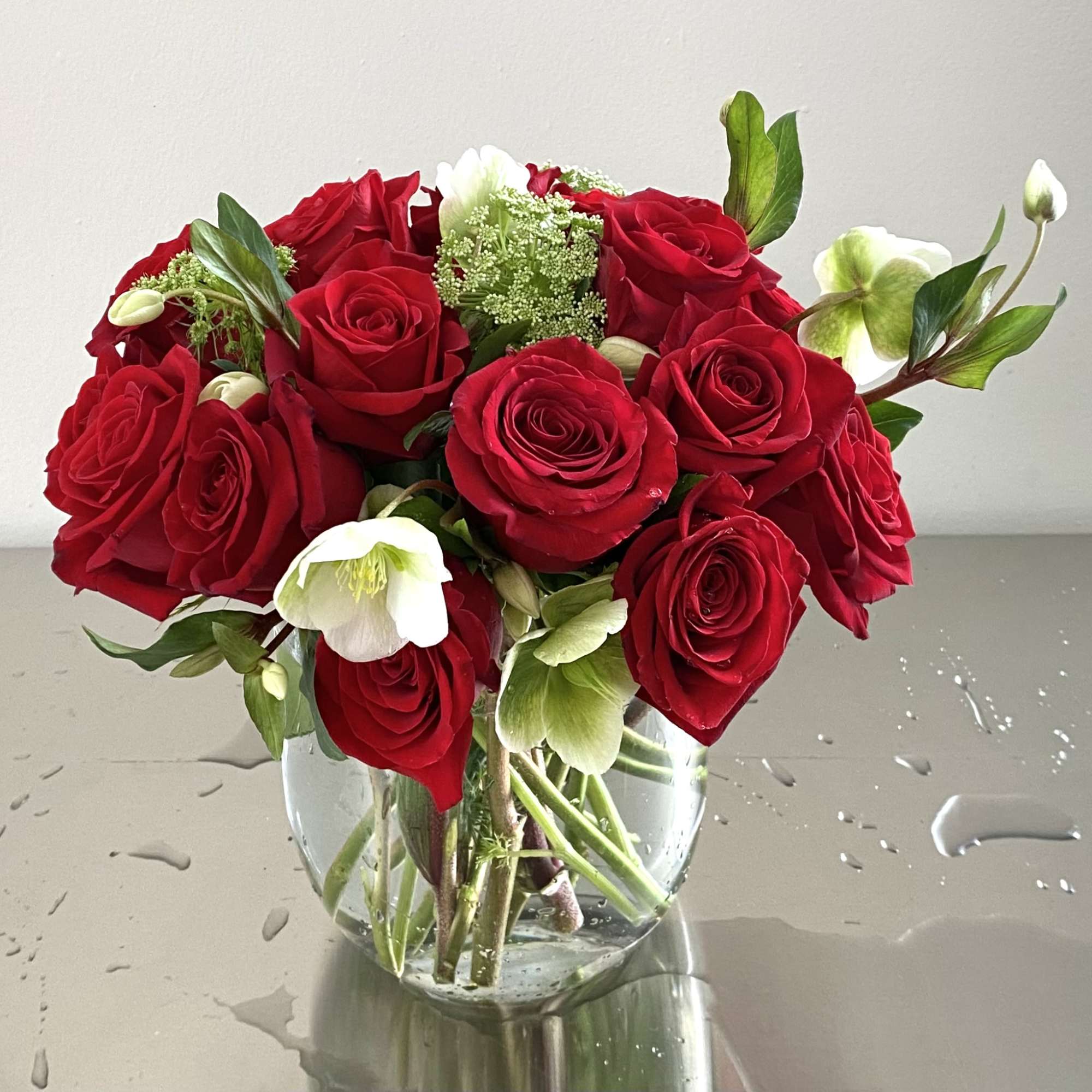 Red roses and white hellebores in a clear glass vase