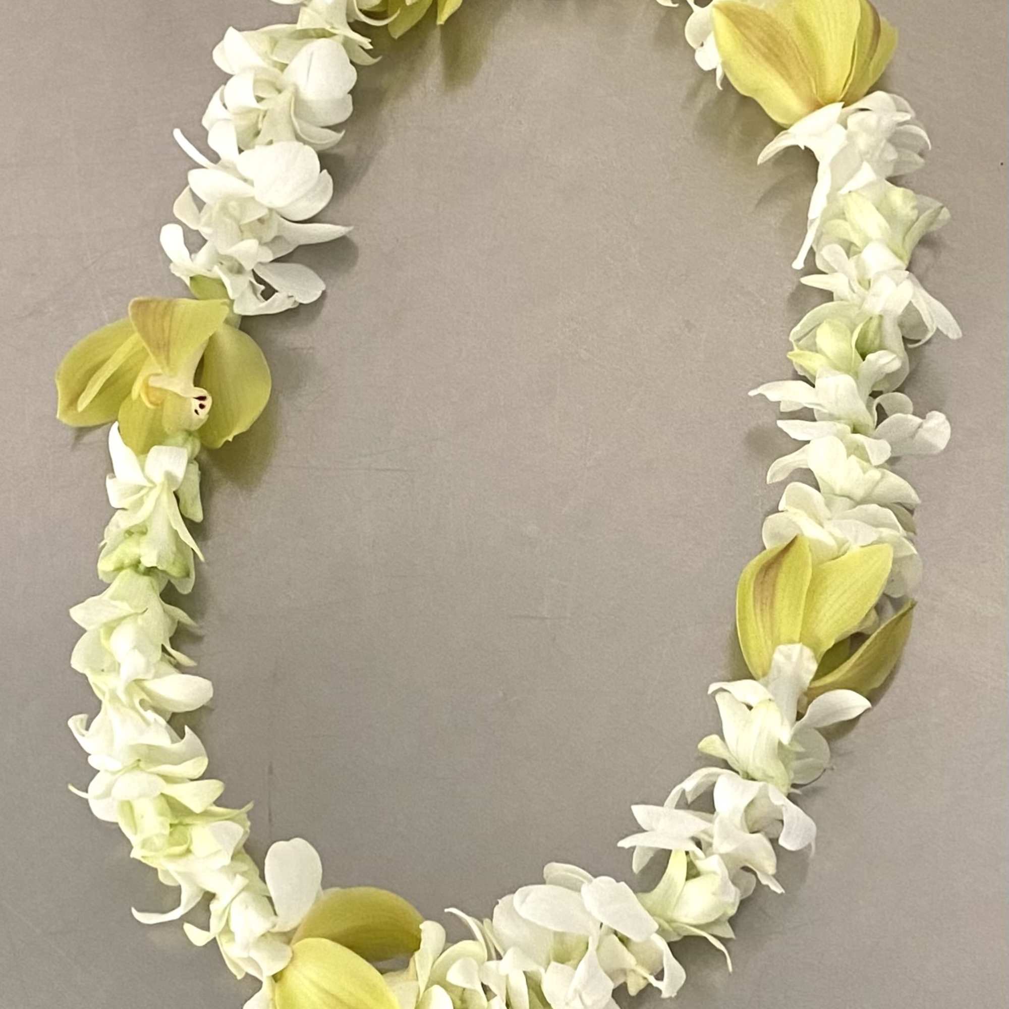 Yellow and white floral lei on a gray background