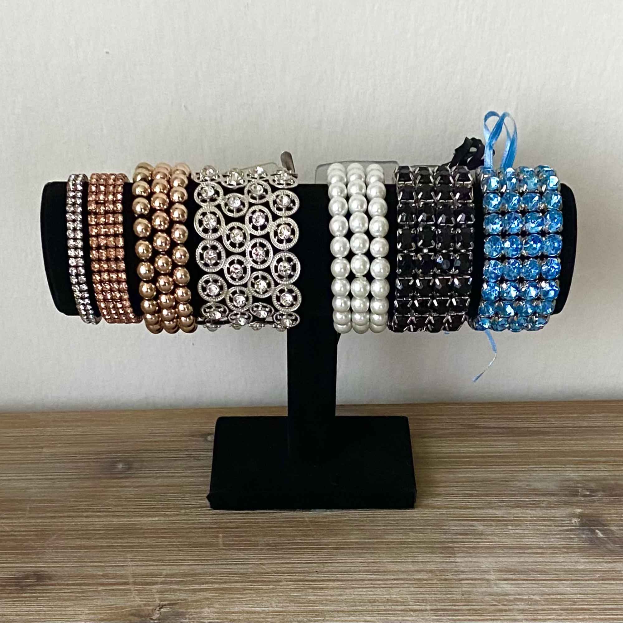 Display stand holding several beaded bracelets in metallic and blue tones