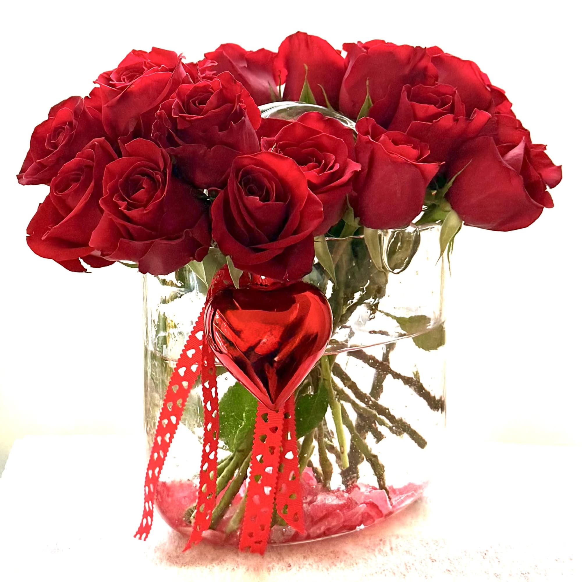 Red roses in a clear glass vase with a red heart ornament