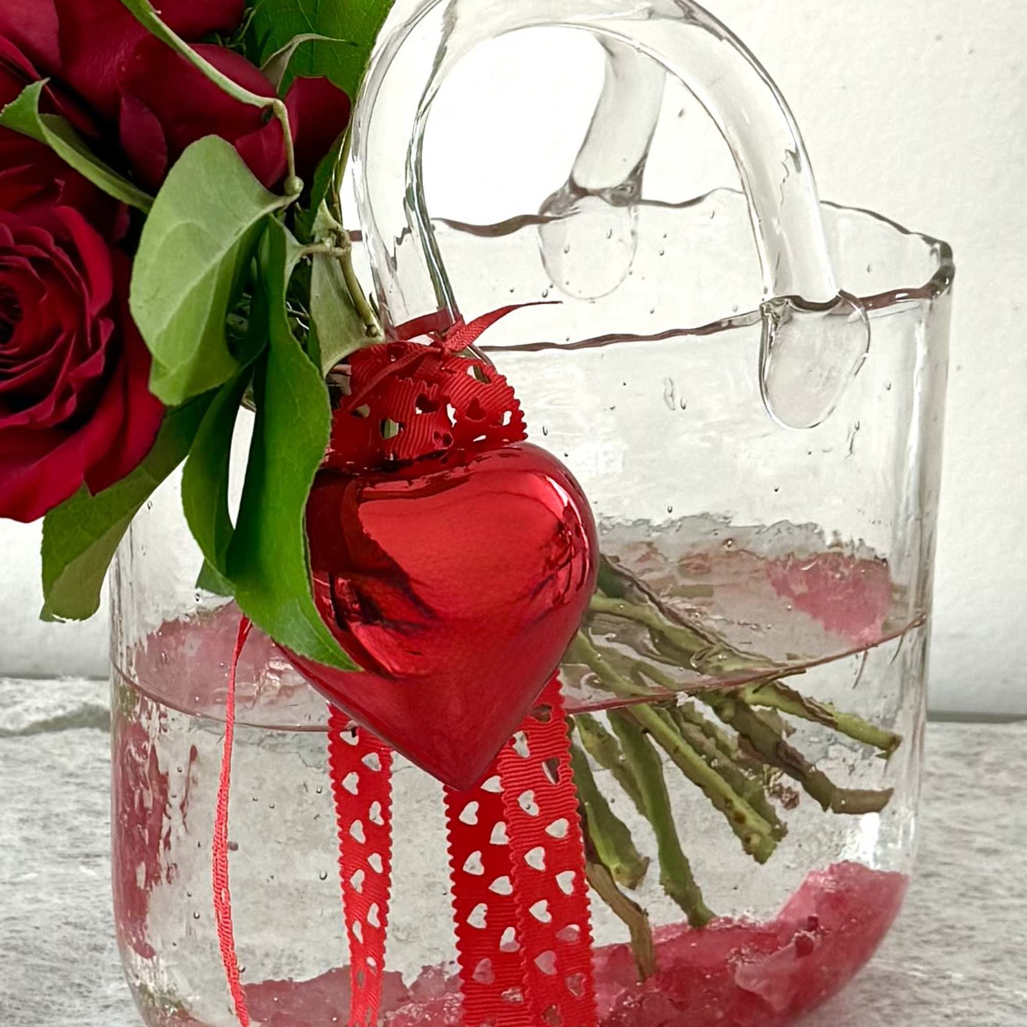 Red roses in a clear glass vase with a red heart ornament, photo 2 of 5