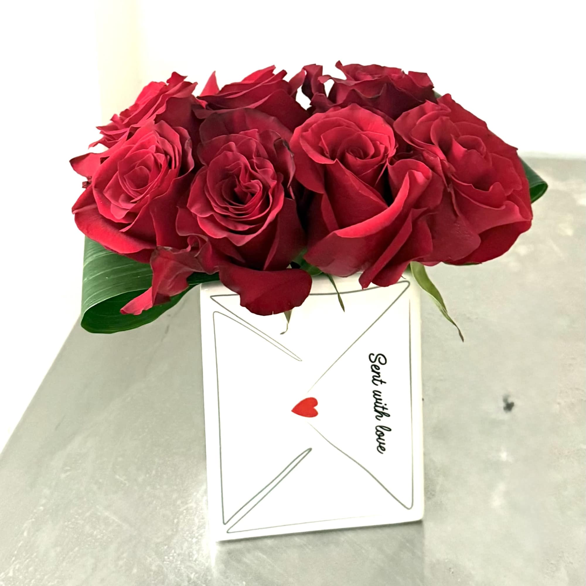 Red roses arranged in a white gift box with a love note