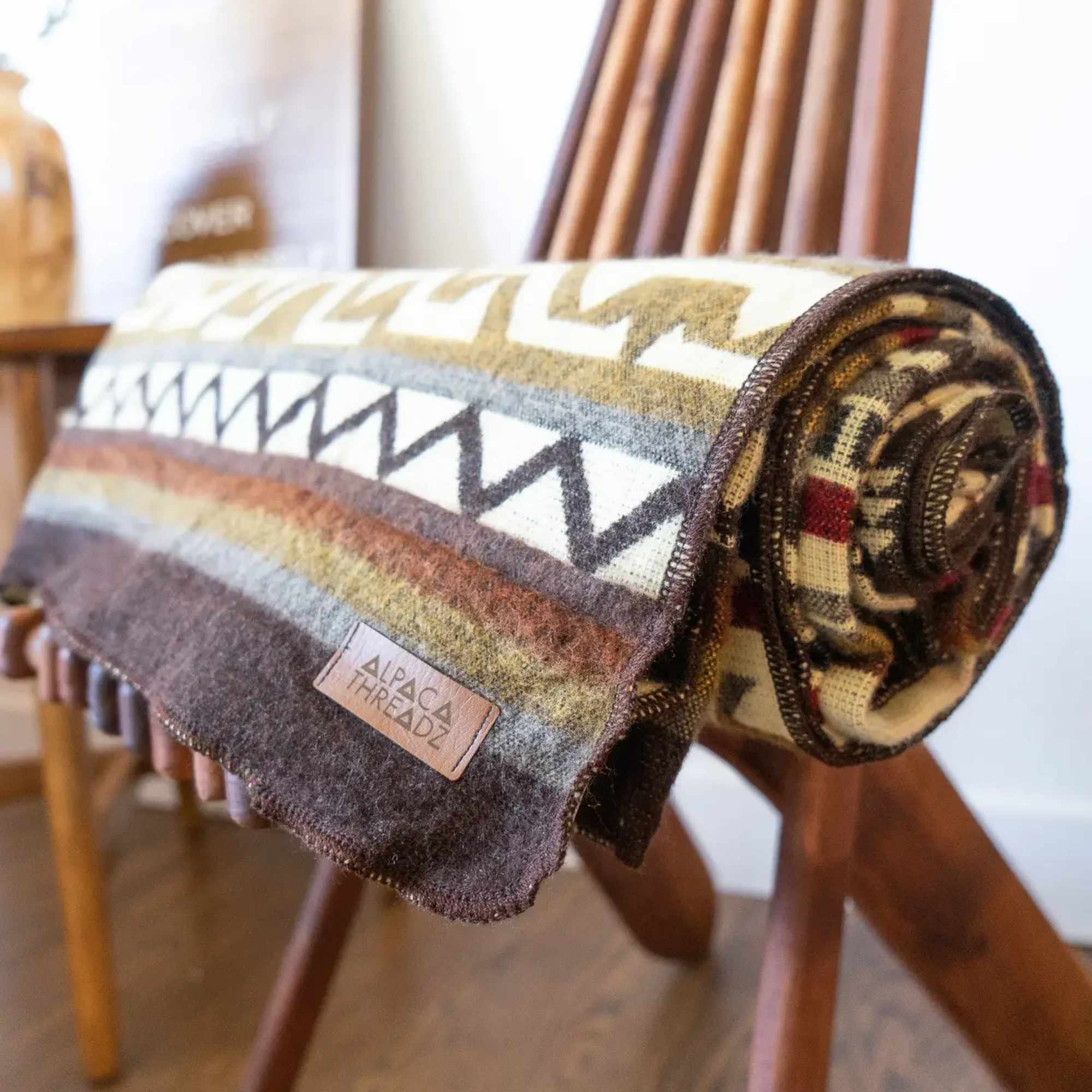 Rolled patterned blanket draped over a wooden chair