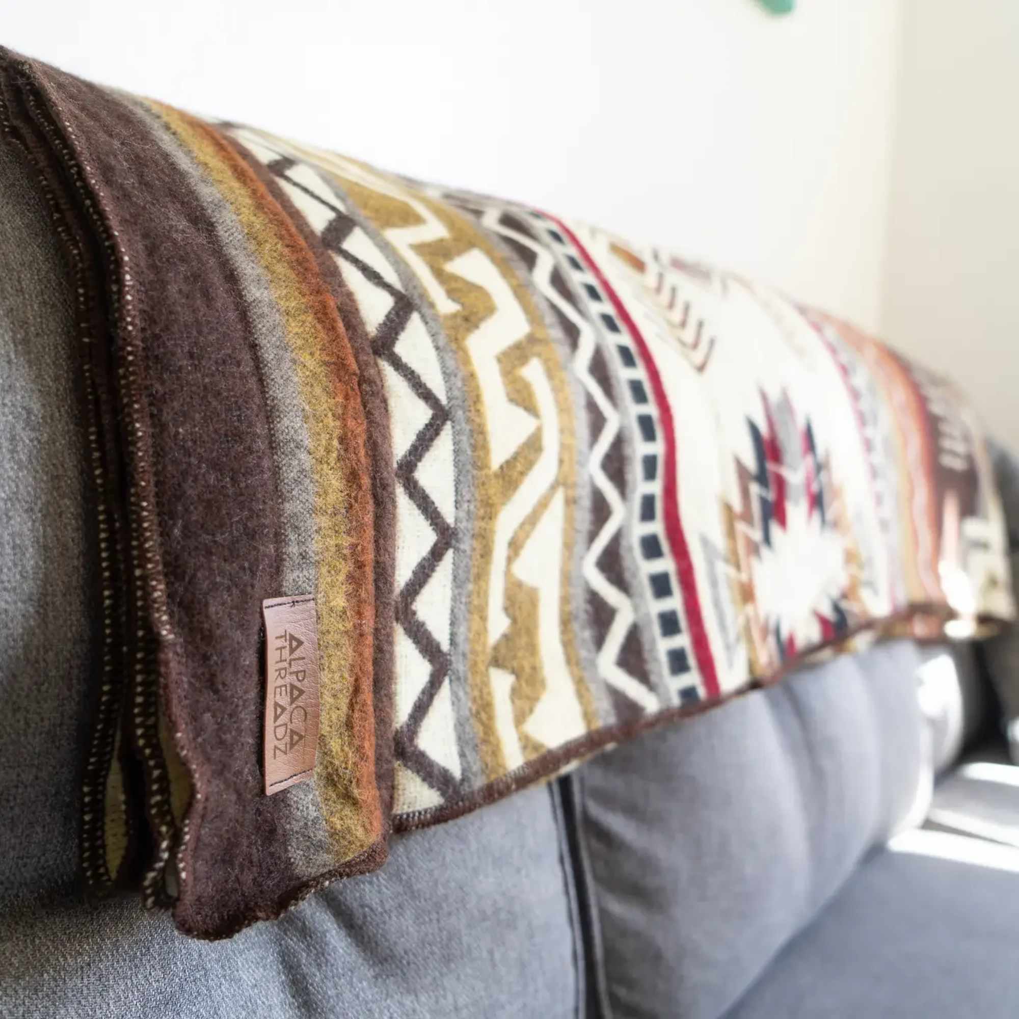 Patterned throw blanket draped over a gray sofa