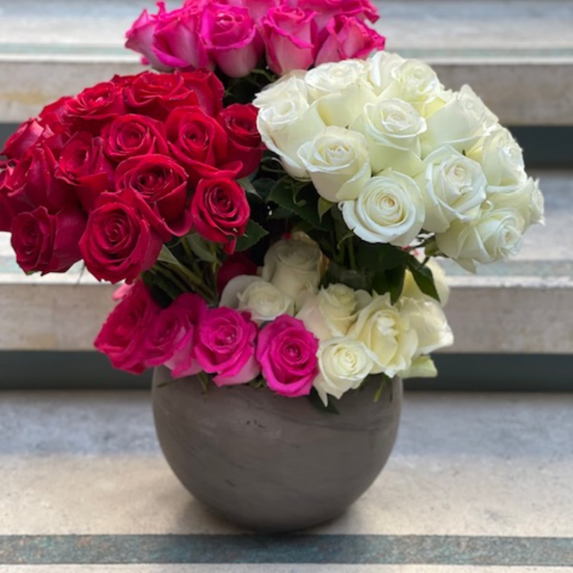Bouquet of pink, red, and white roses in a round vase