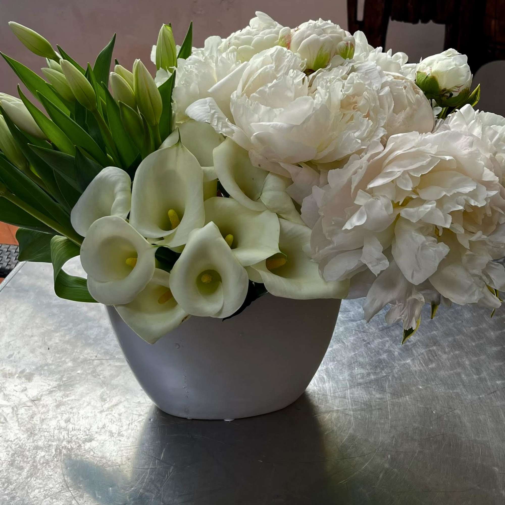 White flowers and calla lilies arranged in a gray vase