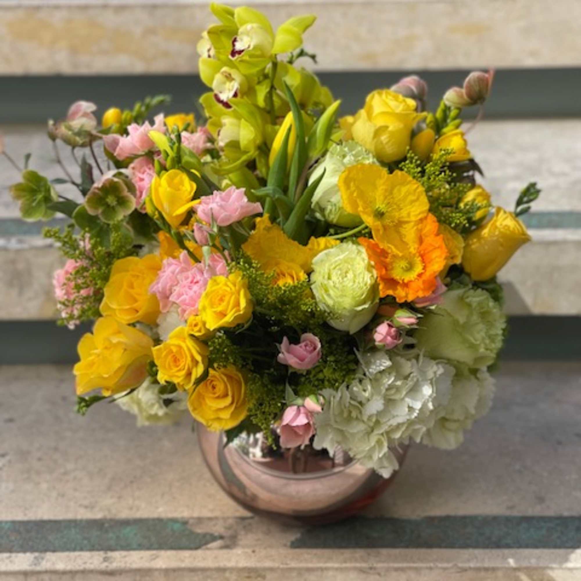 Mixed yellow and pink flower arrangement in a round vase