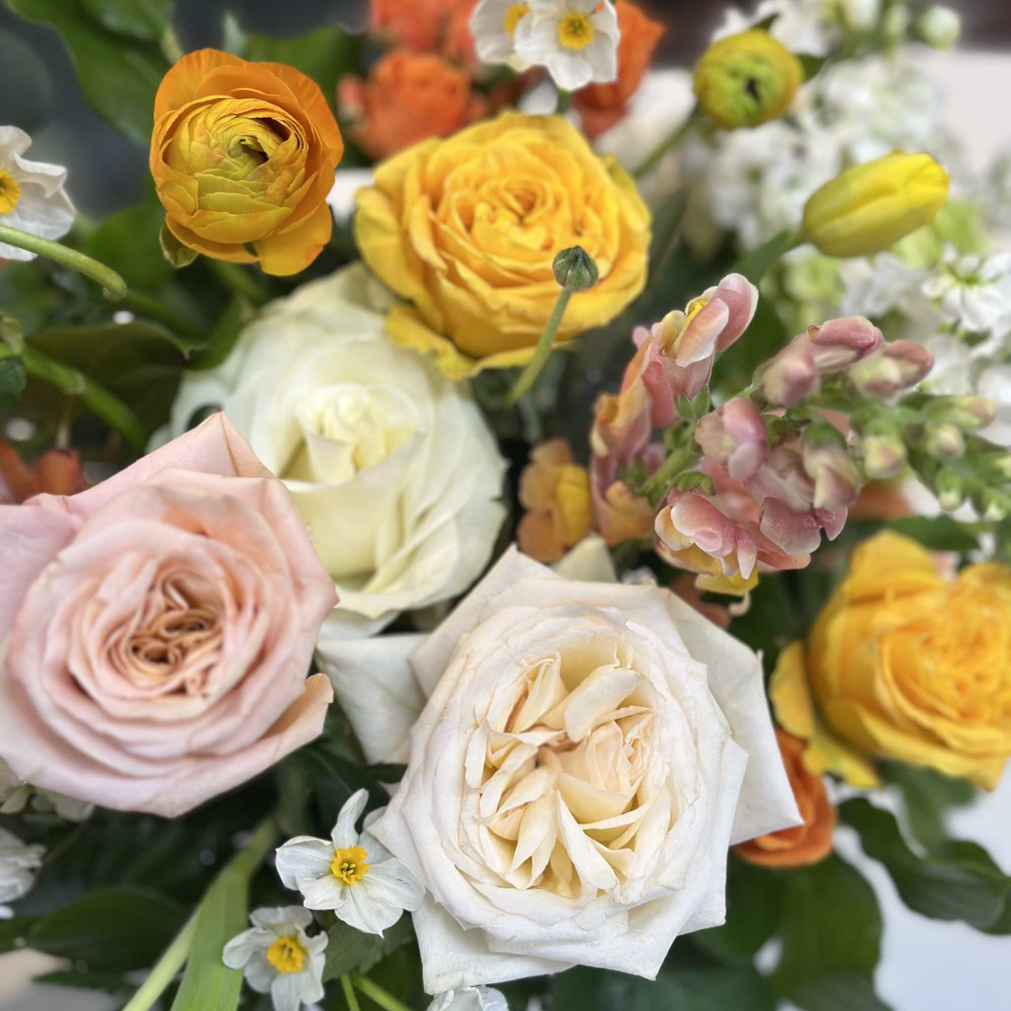 Mixed bouquet of yellow and white blooms with peach roses and small white daffodils