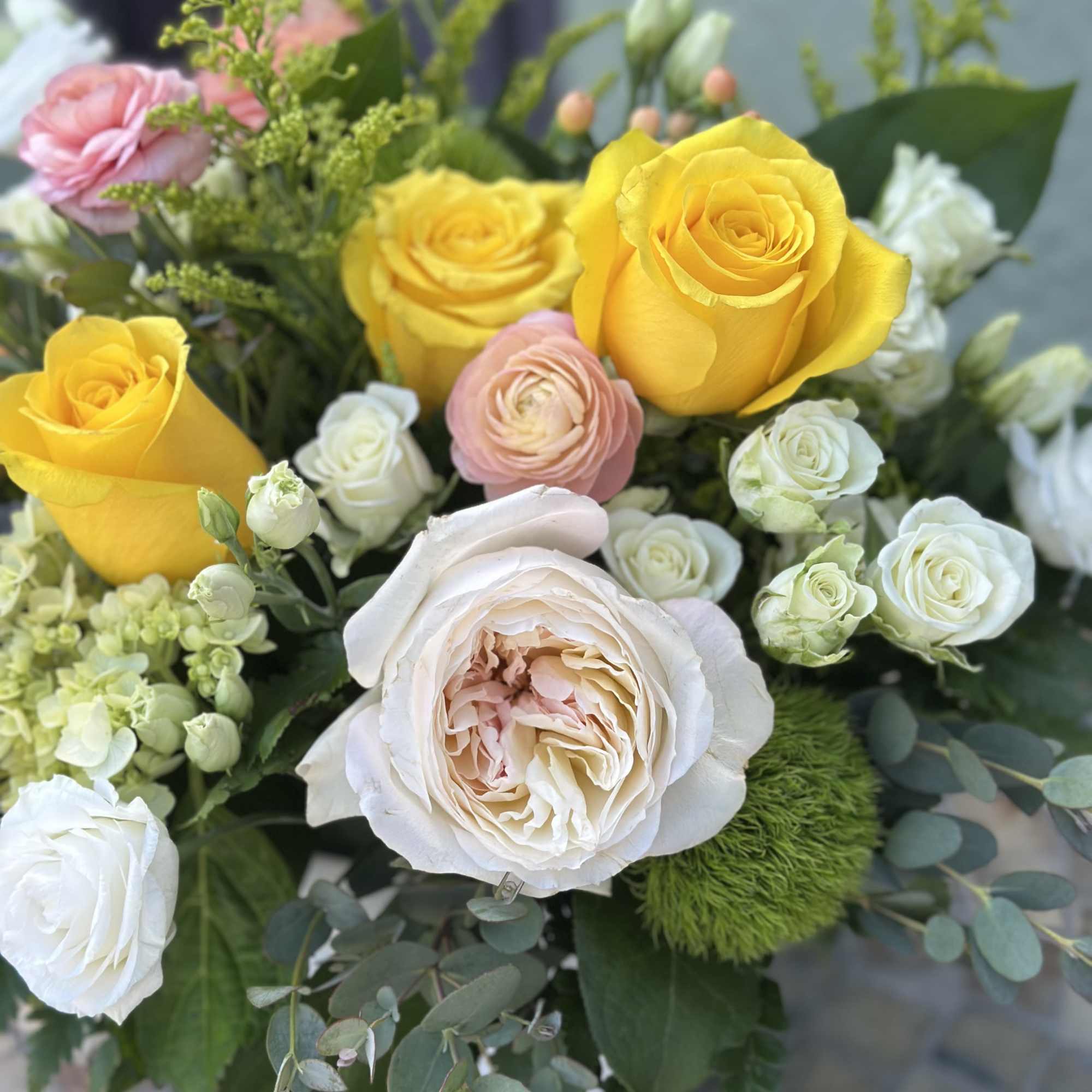 Bright yellow roses take center stage in this garden-style flower arrangement, making