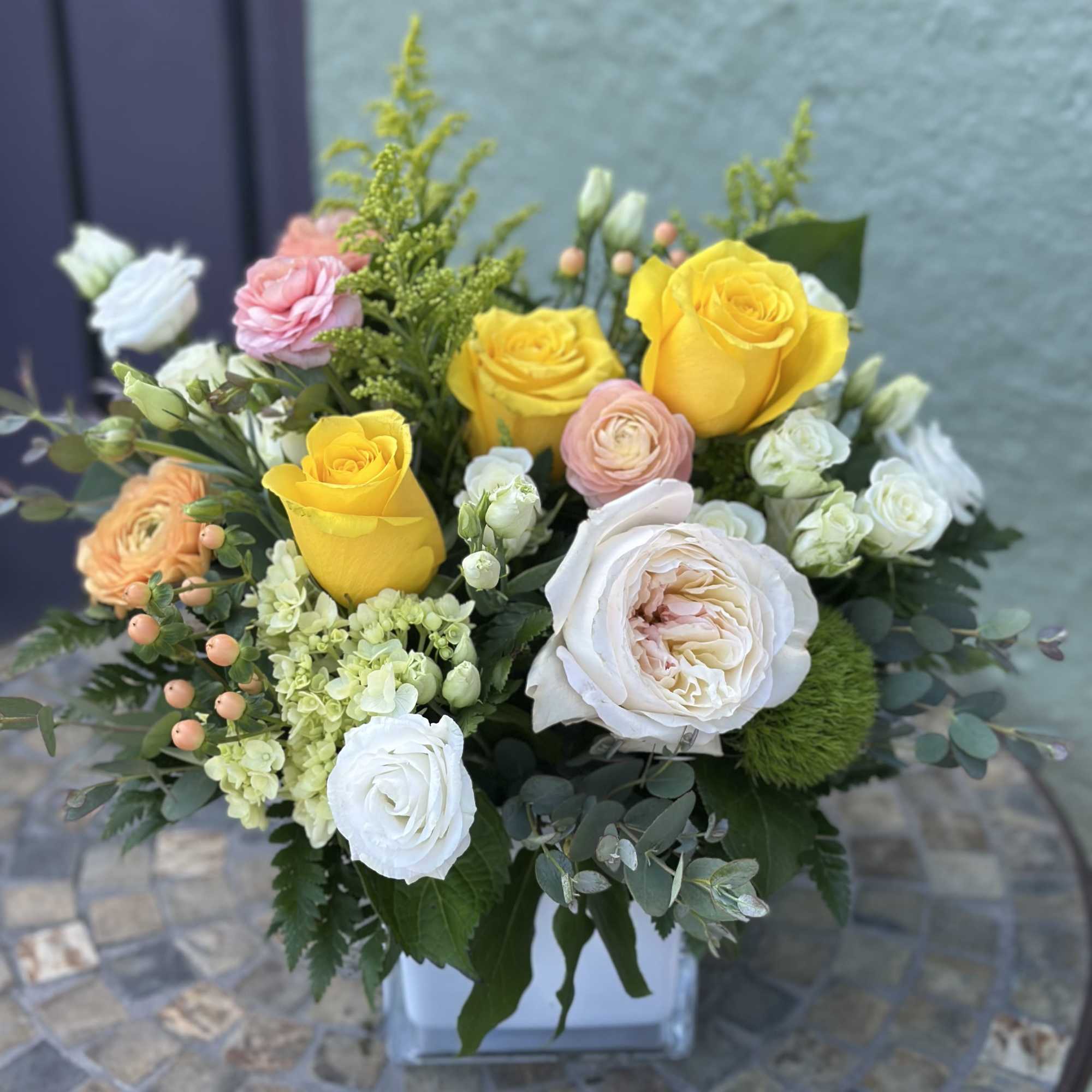 Bright yellow roses take center stage in this garden-style flower arrangement, making