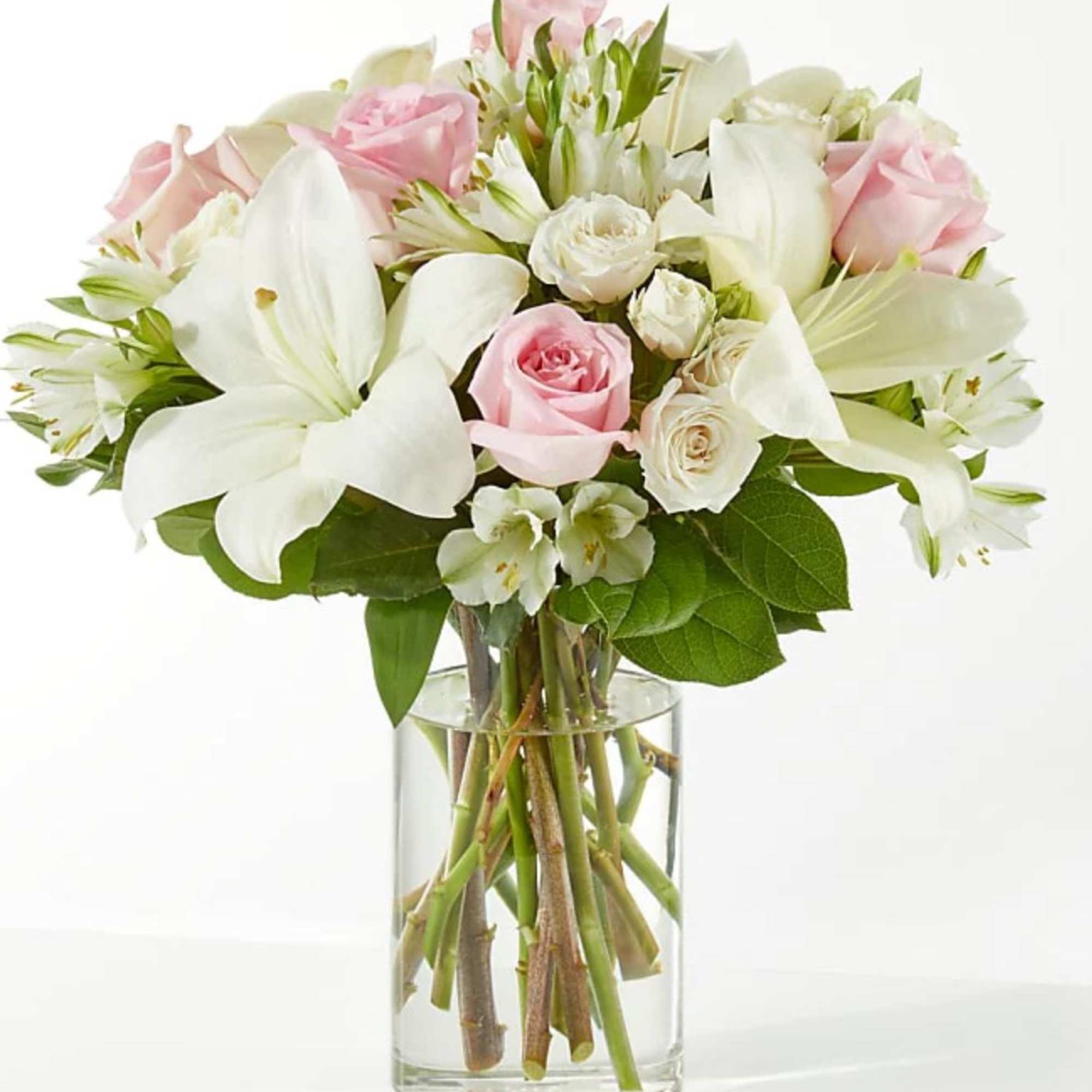 Pink and white bouquet of roses and lilies in a clear glass vase